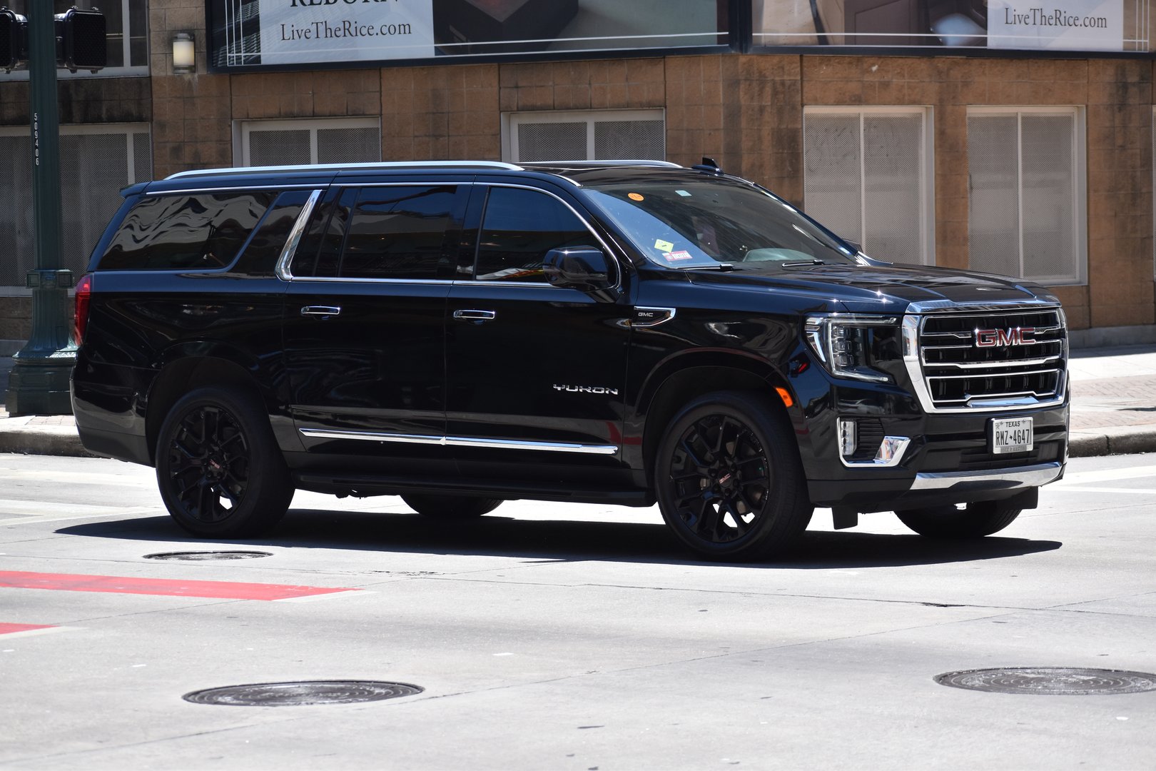 Houston, TX USA - 5/15/2024 - A portrait of a black GMC Yukon XL Denali cruising in a downtown financial district
