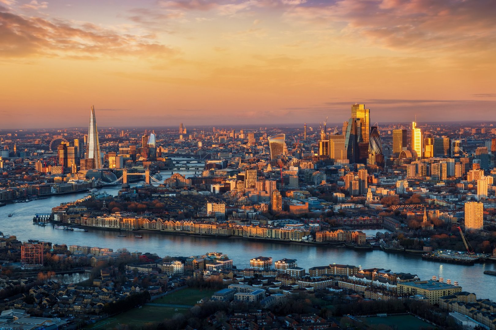 Panoramic, elevated view of the urban London skyline with soft, golden sunlight during sunrise, England