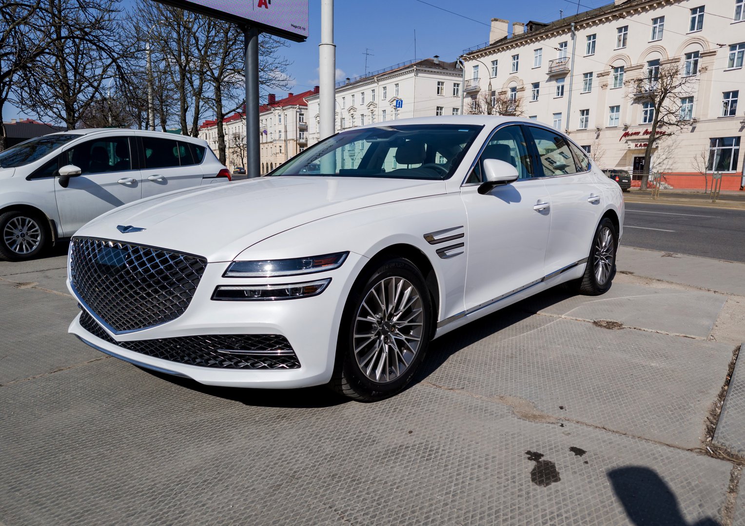 Minsk, Belarus, April 23, 2025 - White Car Genesis g80 parked in city streets. Front view of modern sedan auto