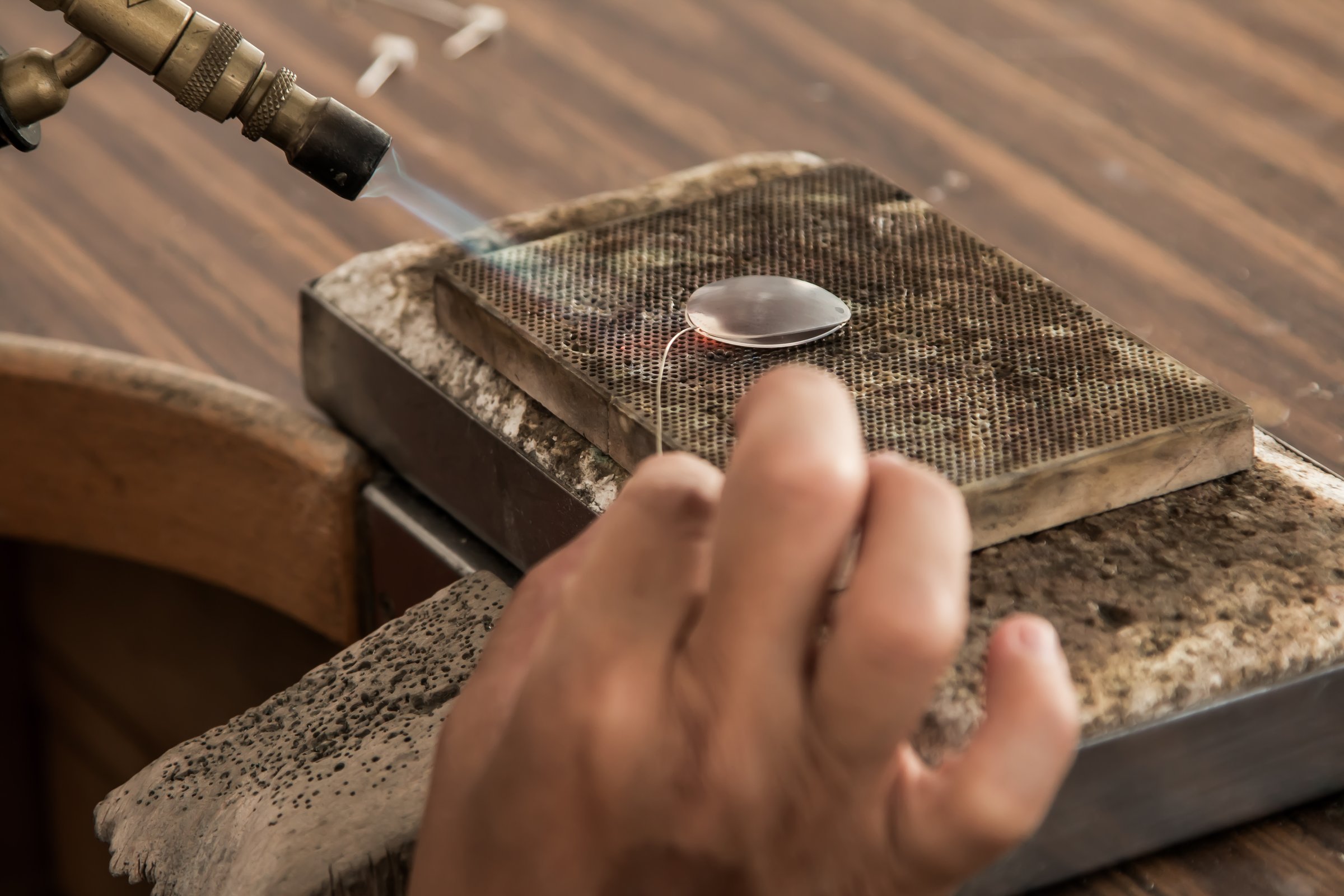 jeweler soldering silver pieces onto earrings