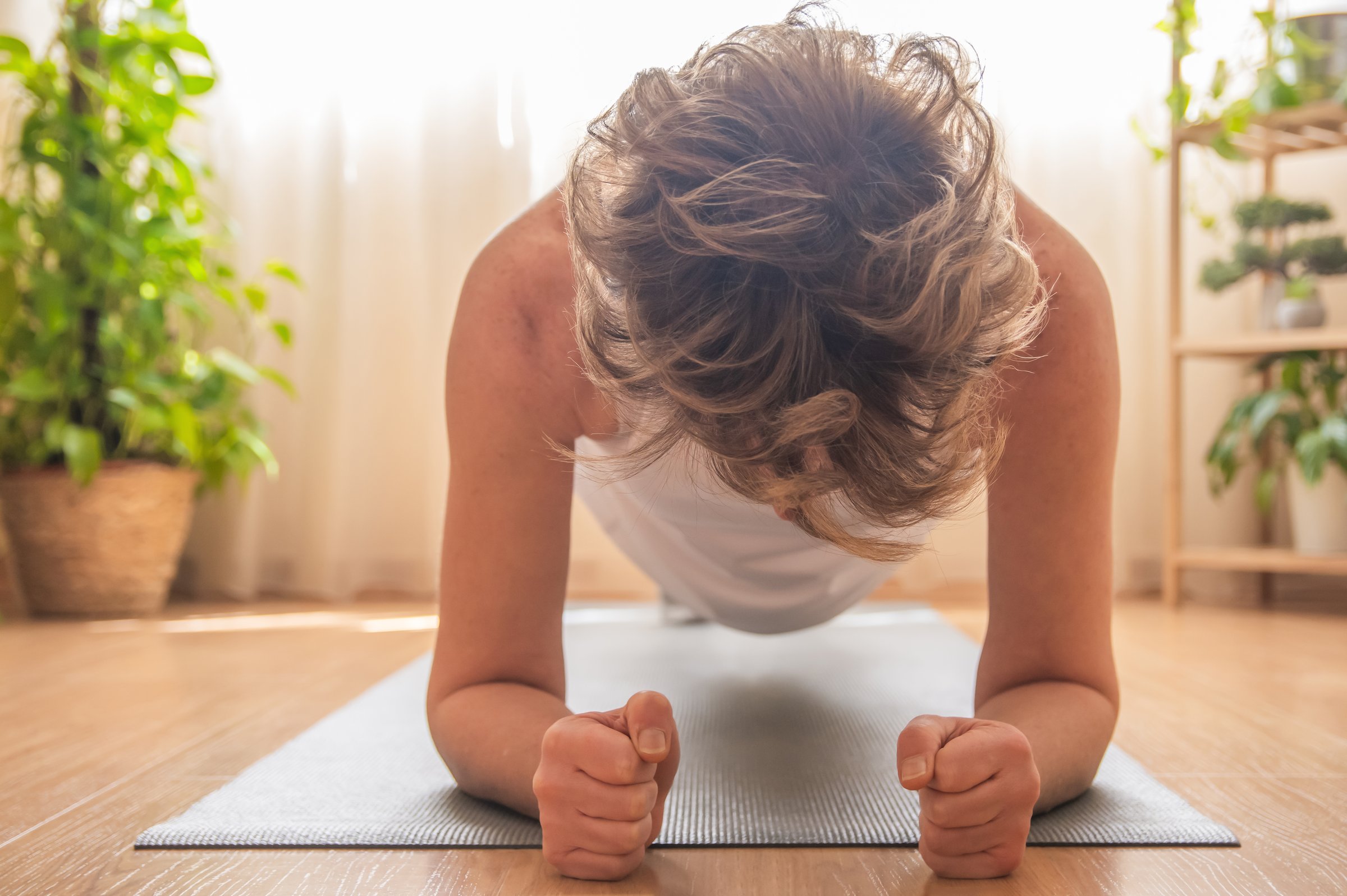 Strong mature woman practicing the plank exercise on a yoga mat at home, concentrating on core strength and enhancing fitness as part of a dedicated wellness routine