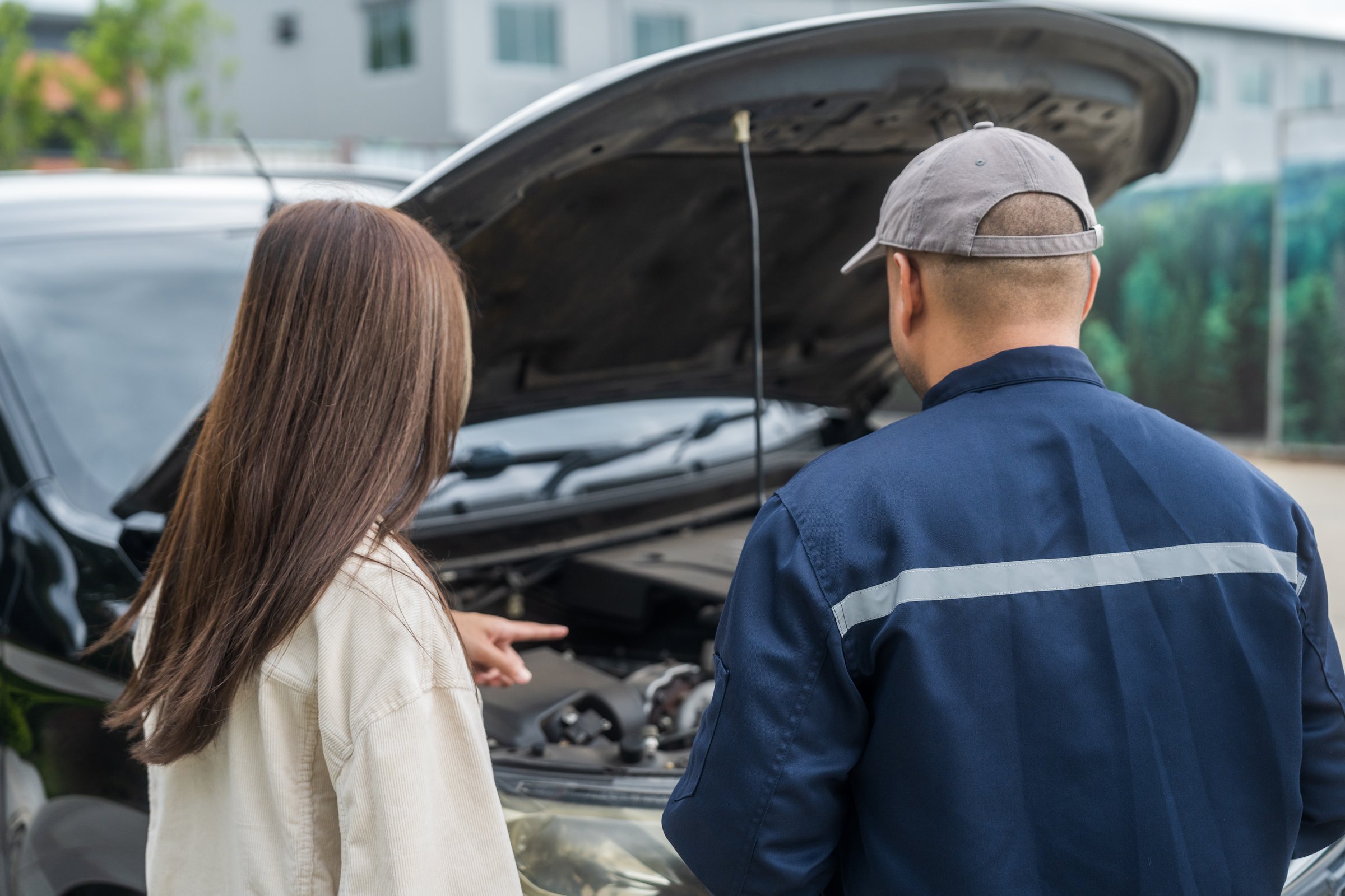 Young female driver call Auto mechanic car service. Broken Down car outside the road help and support customer. Discussing repairs problems to vehicle.