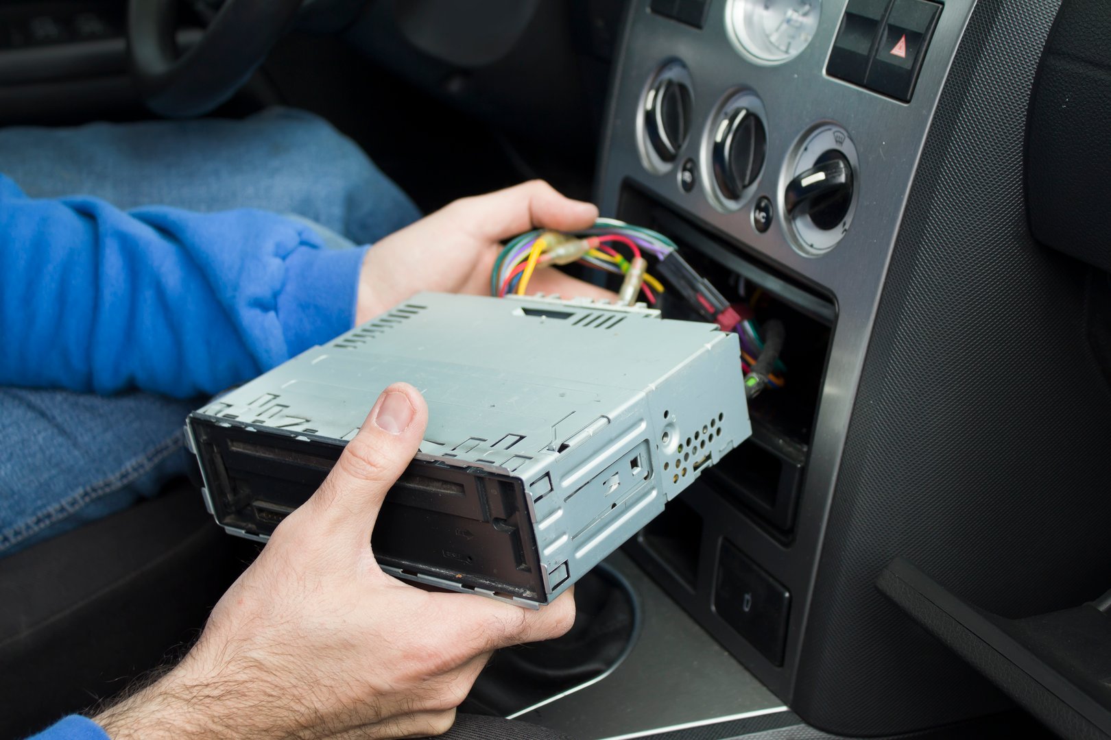 Mechanic puts a car radio into a car radio pocket. Connecting the radio