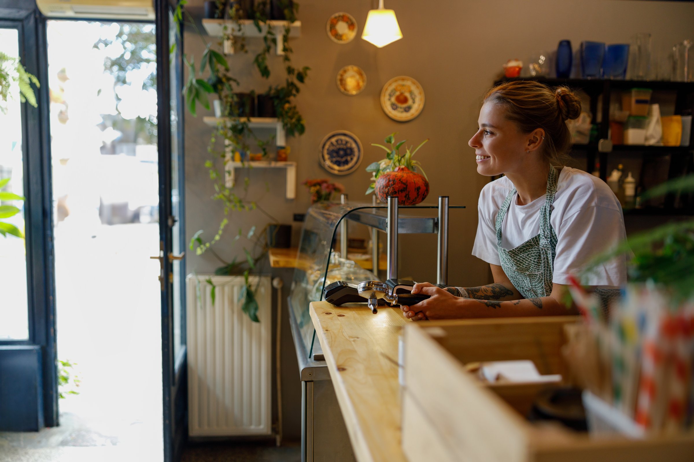 A barista smiles while serving in a charming caf adorned with plants and decor