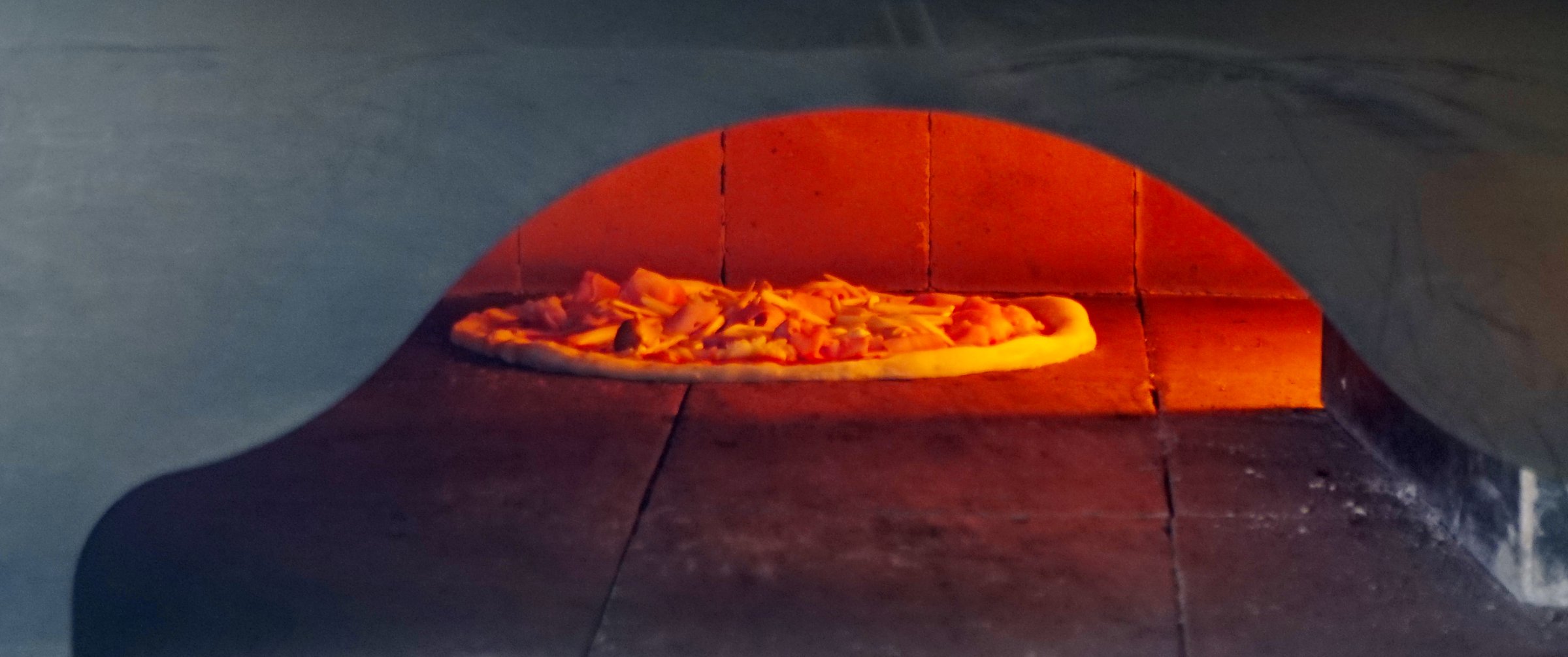 Pizza dough inside the wood-fired oven of a pizzeria