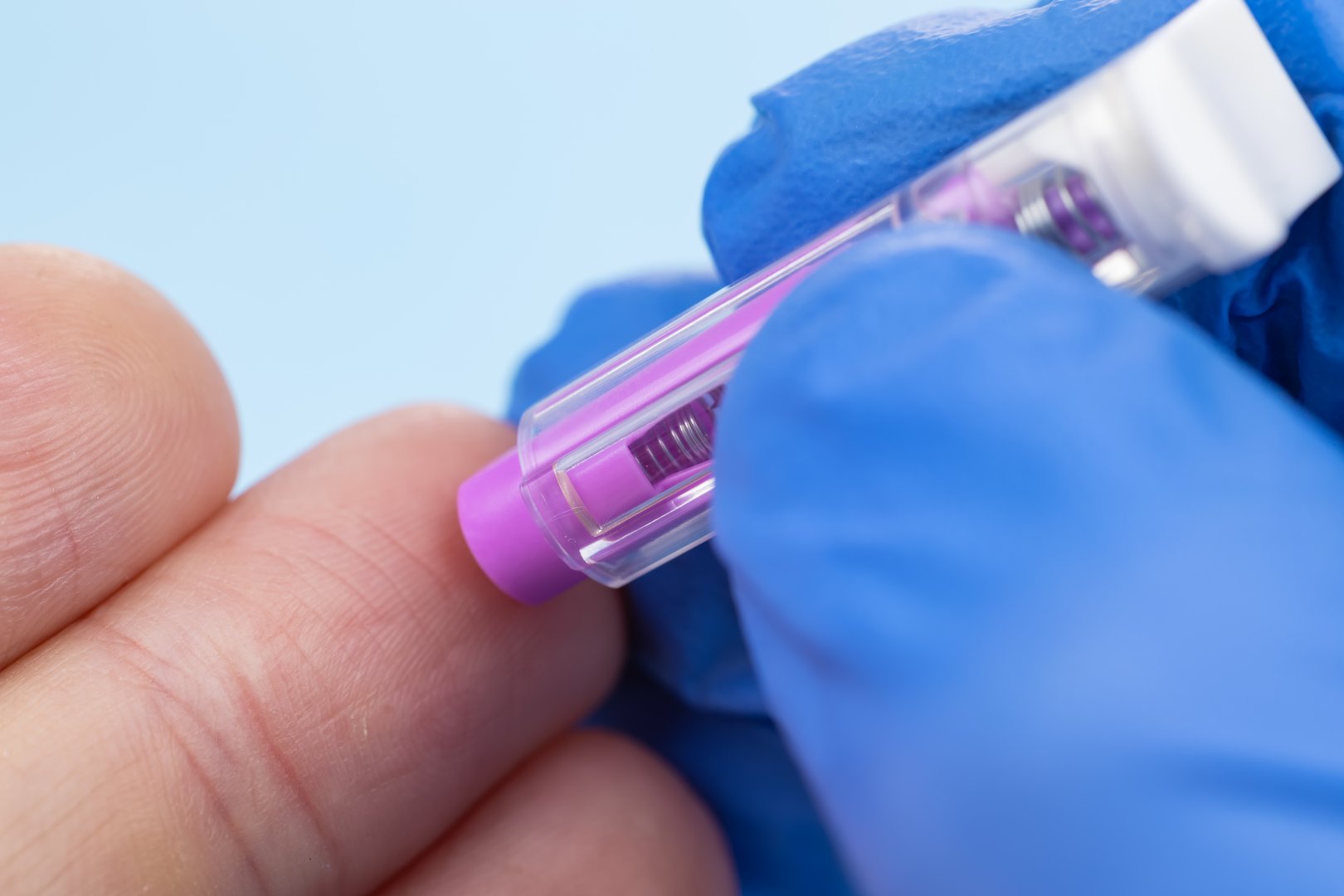 Doctor piercing patients finger with automatic lancet in clinic. Taking blood for close-up analysis, a clinical blood test. Finger prick.