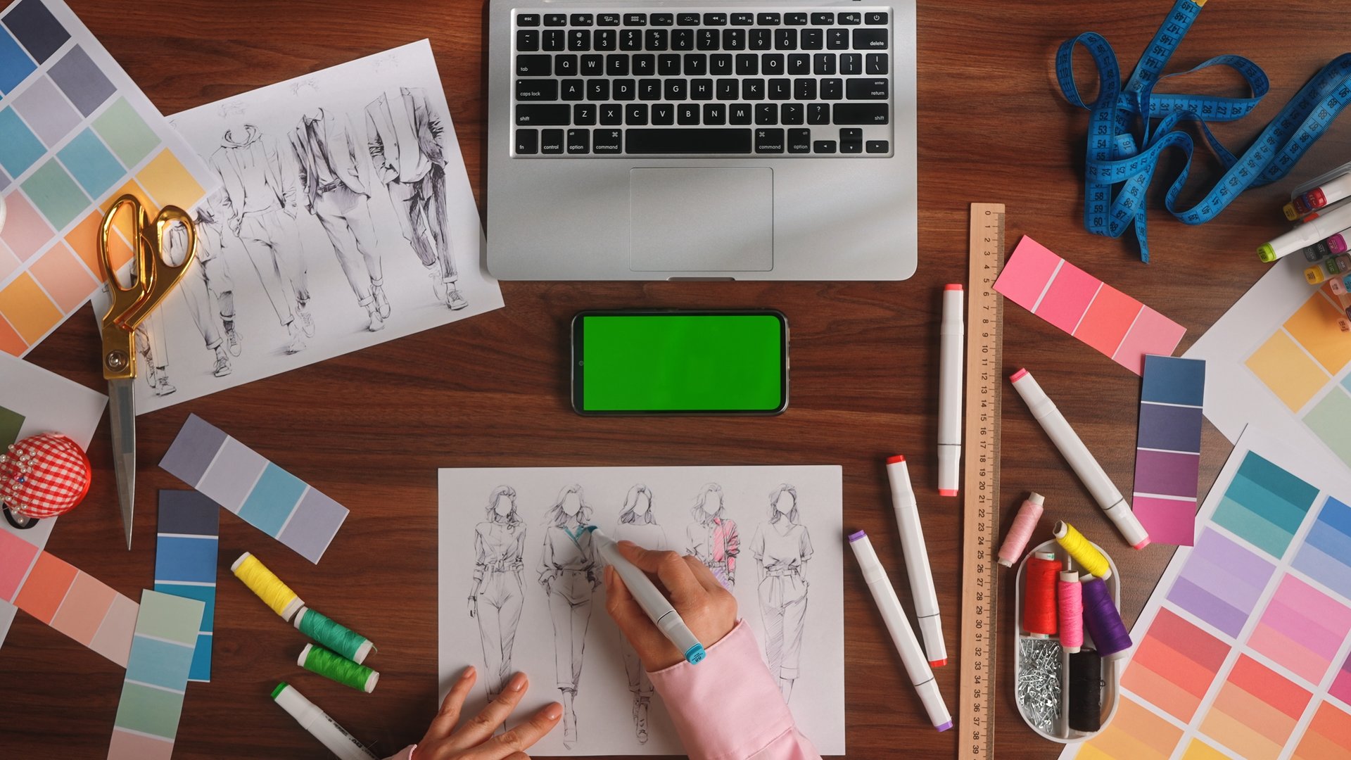 An overhead view of a fashion designers workspace with sketches, tools, and color swatches to inspire creativity.