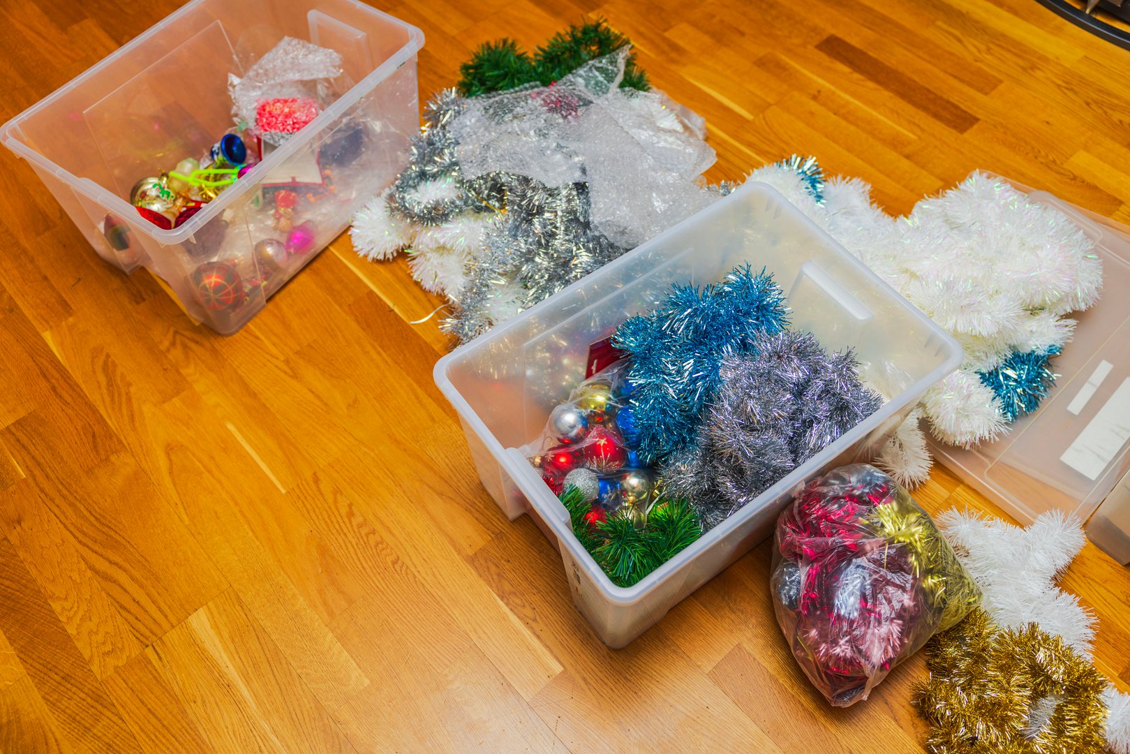 Colorful Christmas garlands and ornaments lying in plastic boxes