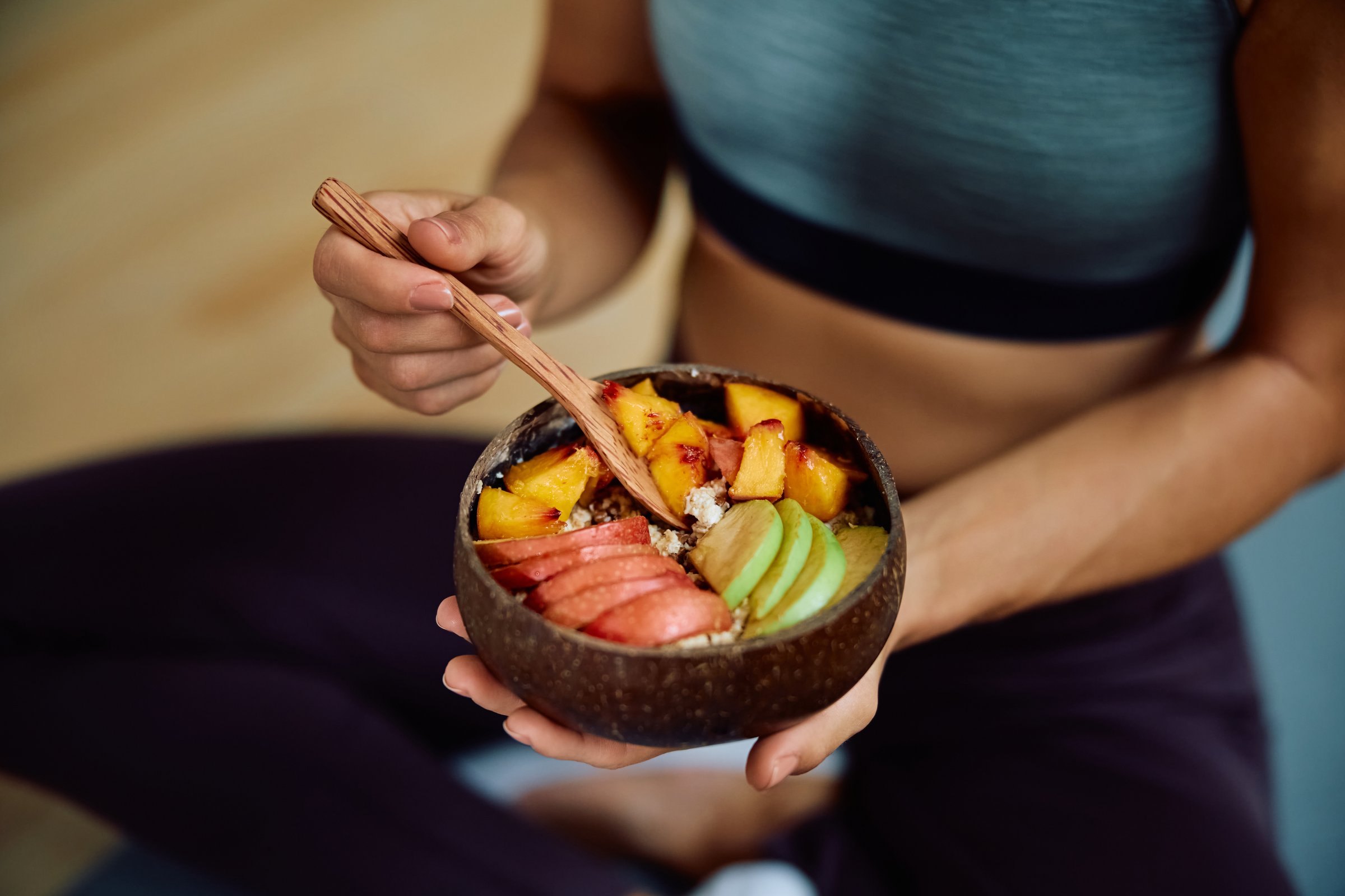 Close up of woman eating fruit salad after exercising.