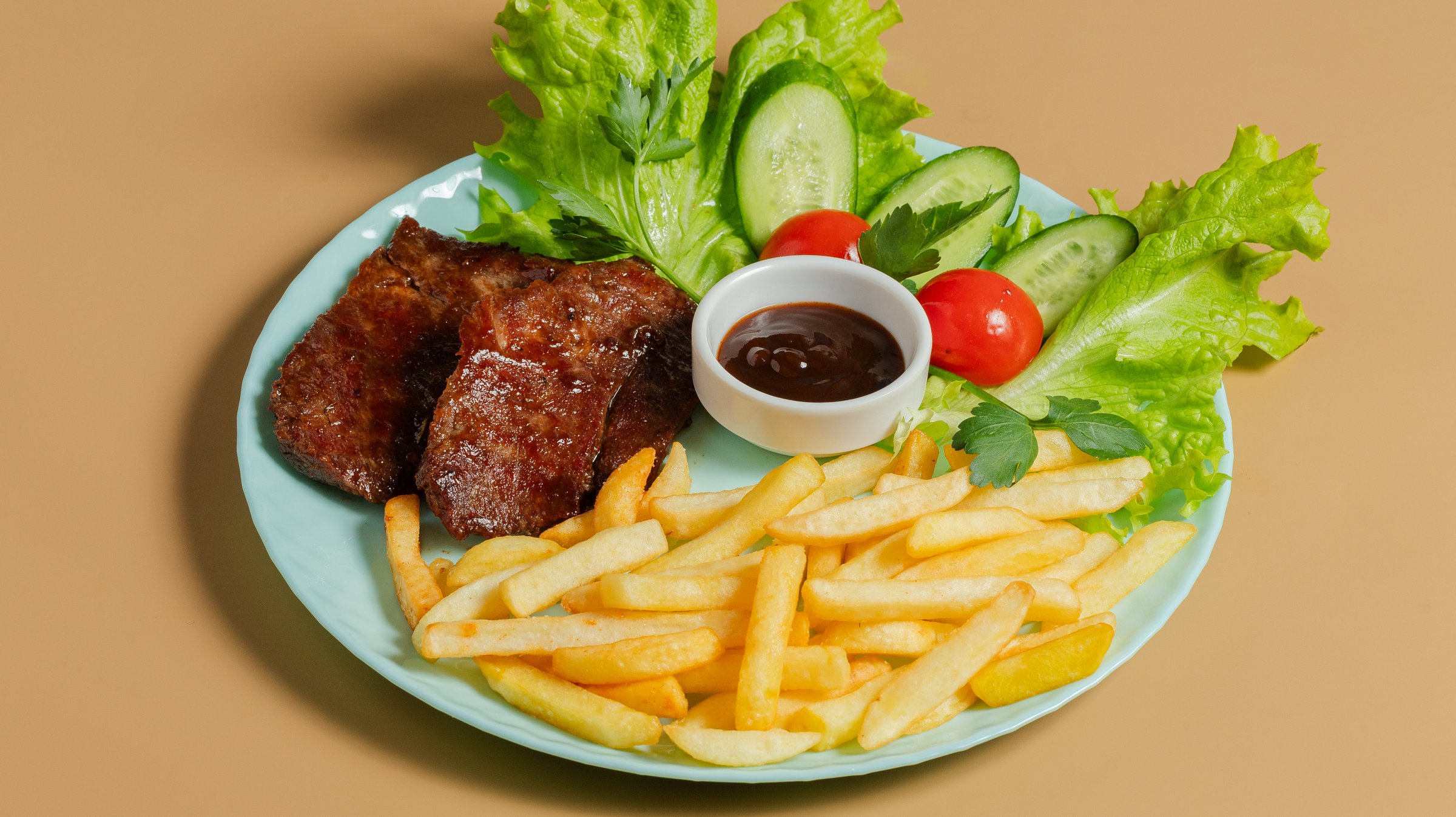 Beef steak and fries in plate with vegetables