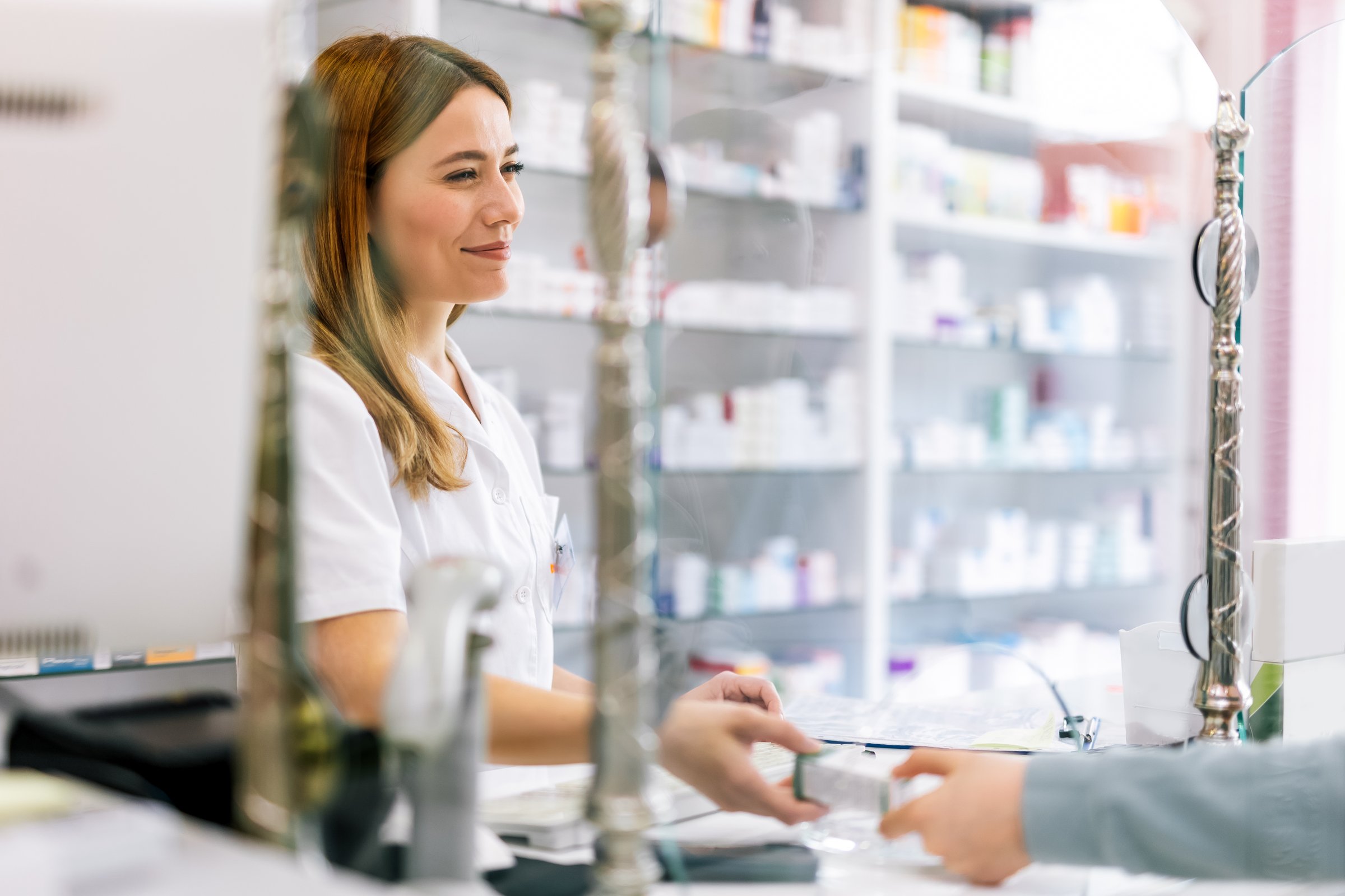 Woman pharmacist  consulting customer at counter for prescription drugs or medicine at the pharmacy. Female doctor giving patient medical antibiotics at the pharmacy