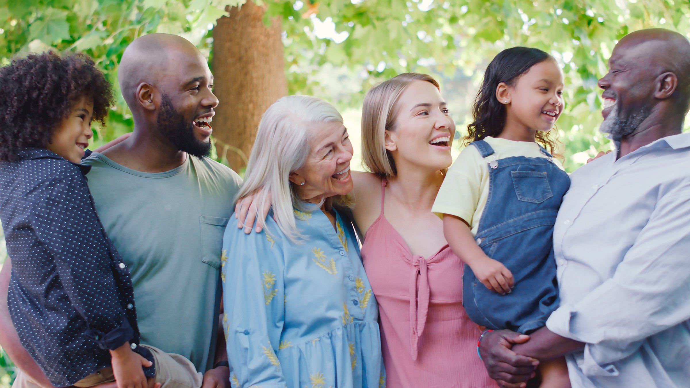 Portrait Of Multi-Generation Family Standing In Garden Smiling At Camera