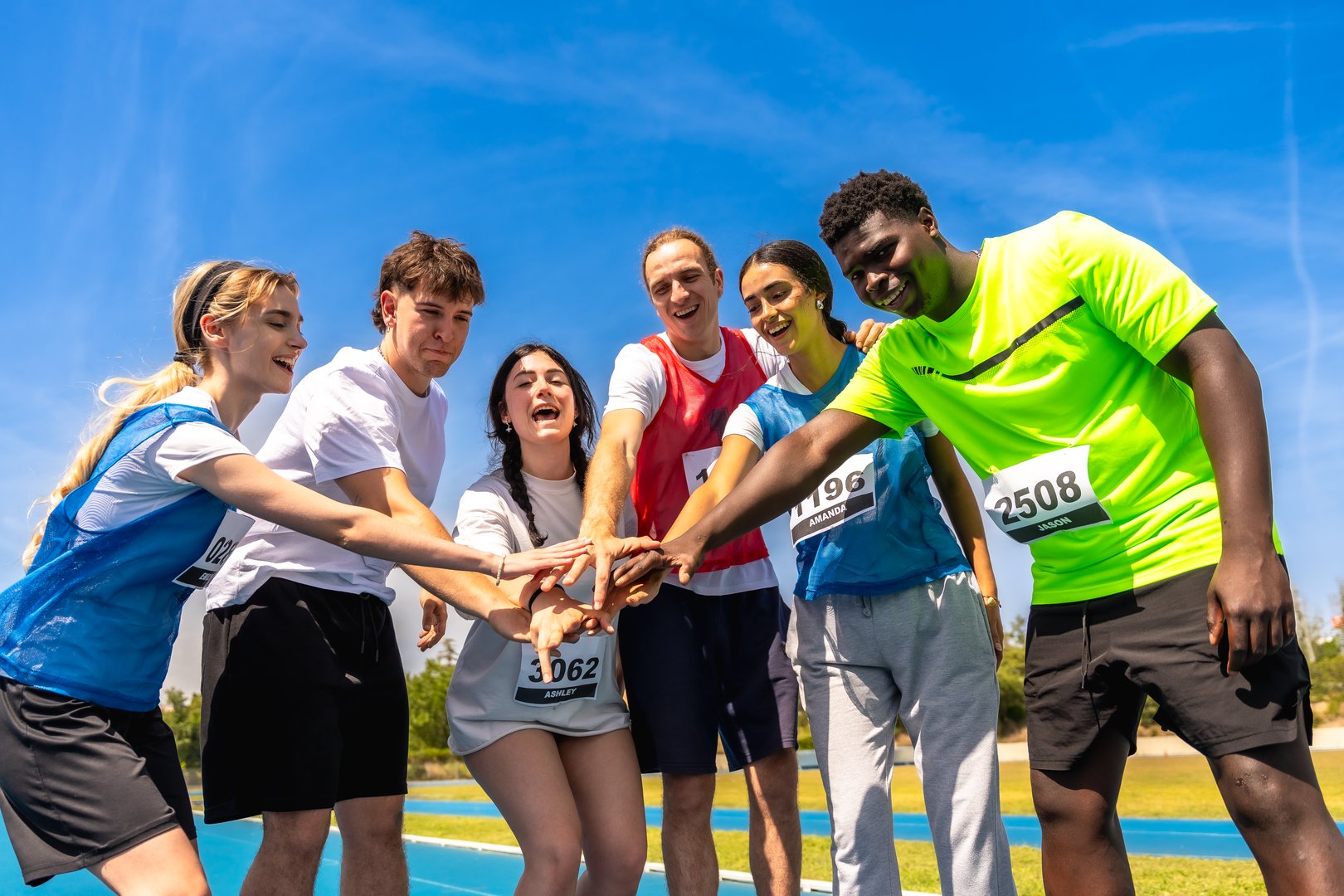 Group of young athletes stacking hands before a race, demonstrating their teamwork and motivation