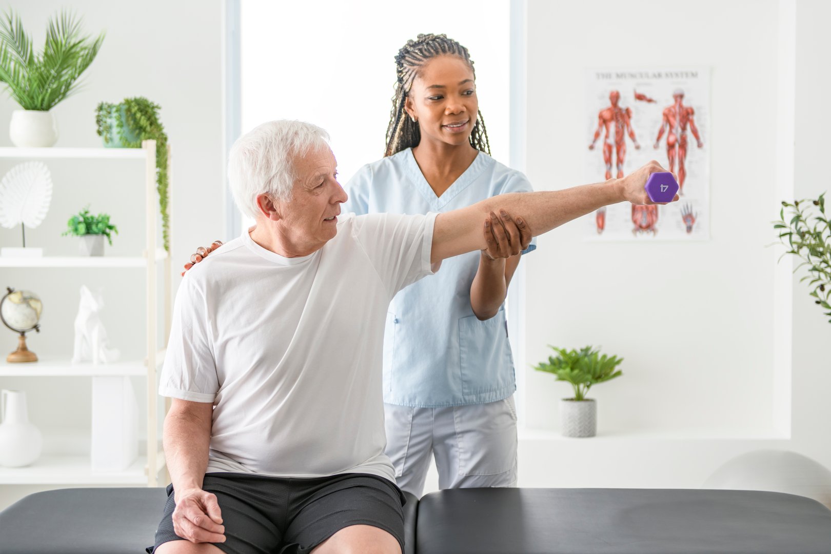 A black Physiotherapist helping senior man with in clinic. Elderly man undergoing physiotherapy treatment for injury