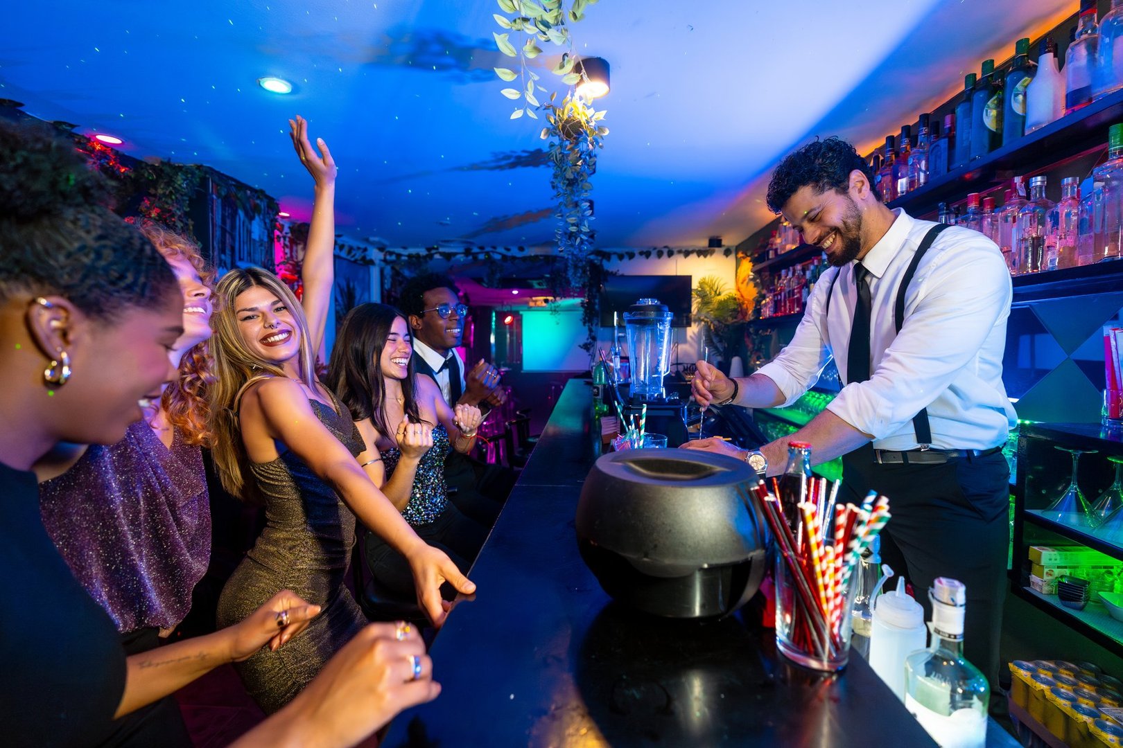 Young adults enjoying vibrant nightlife, dancing energetically while a bartender skillfully prepares colorful cocktails at the bar