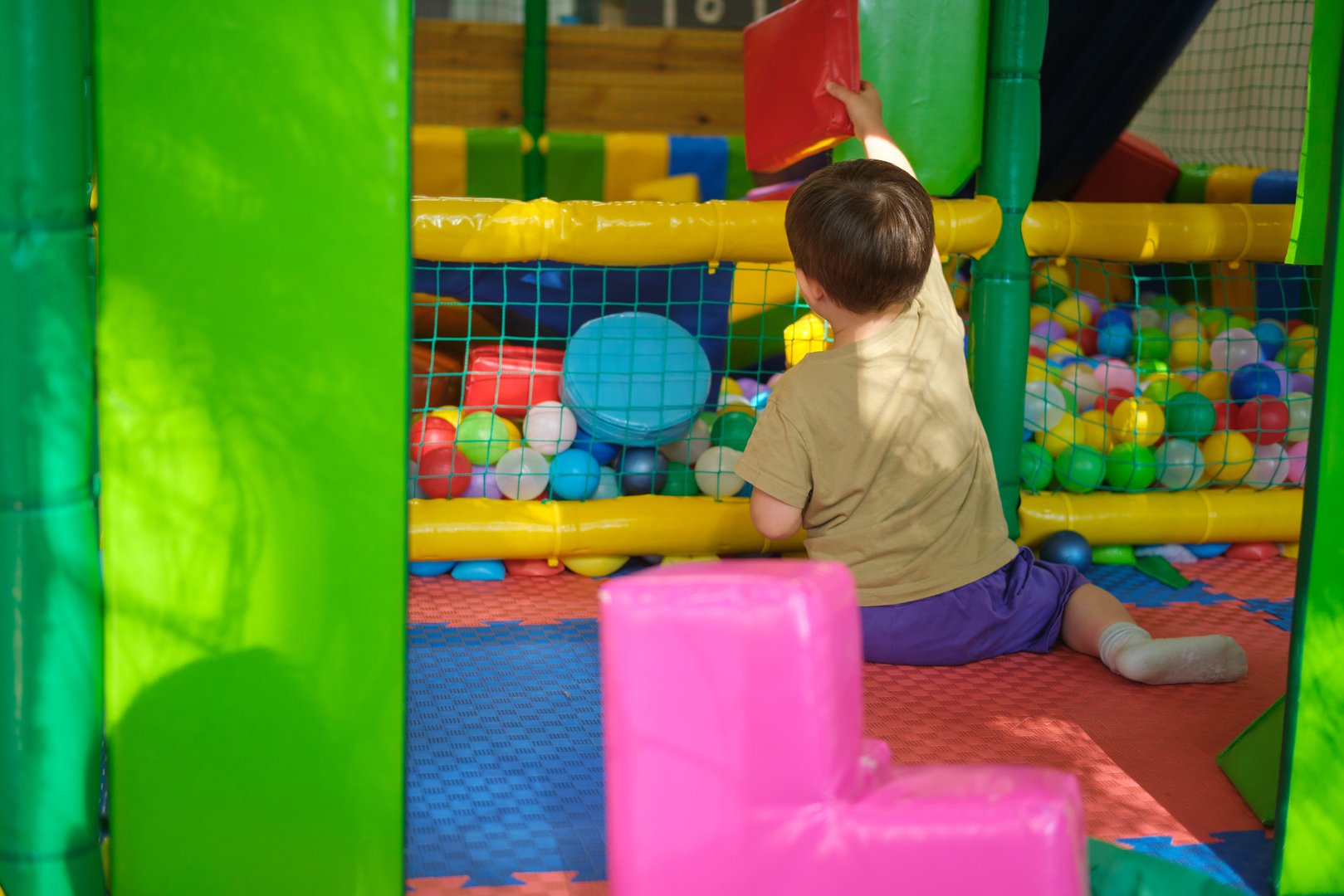 Child playing with soft blocks in indoor ball pit. Indoor playground photography for design and print. Kid aged three (three year old boy)
