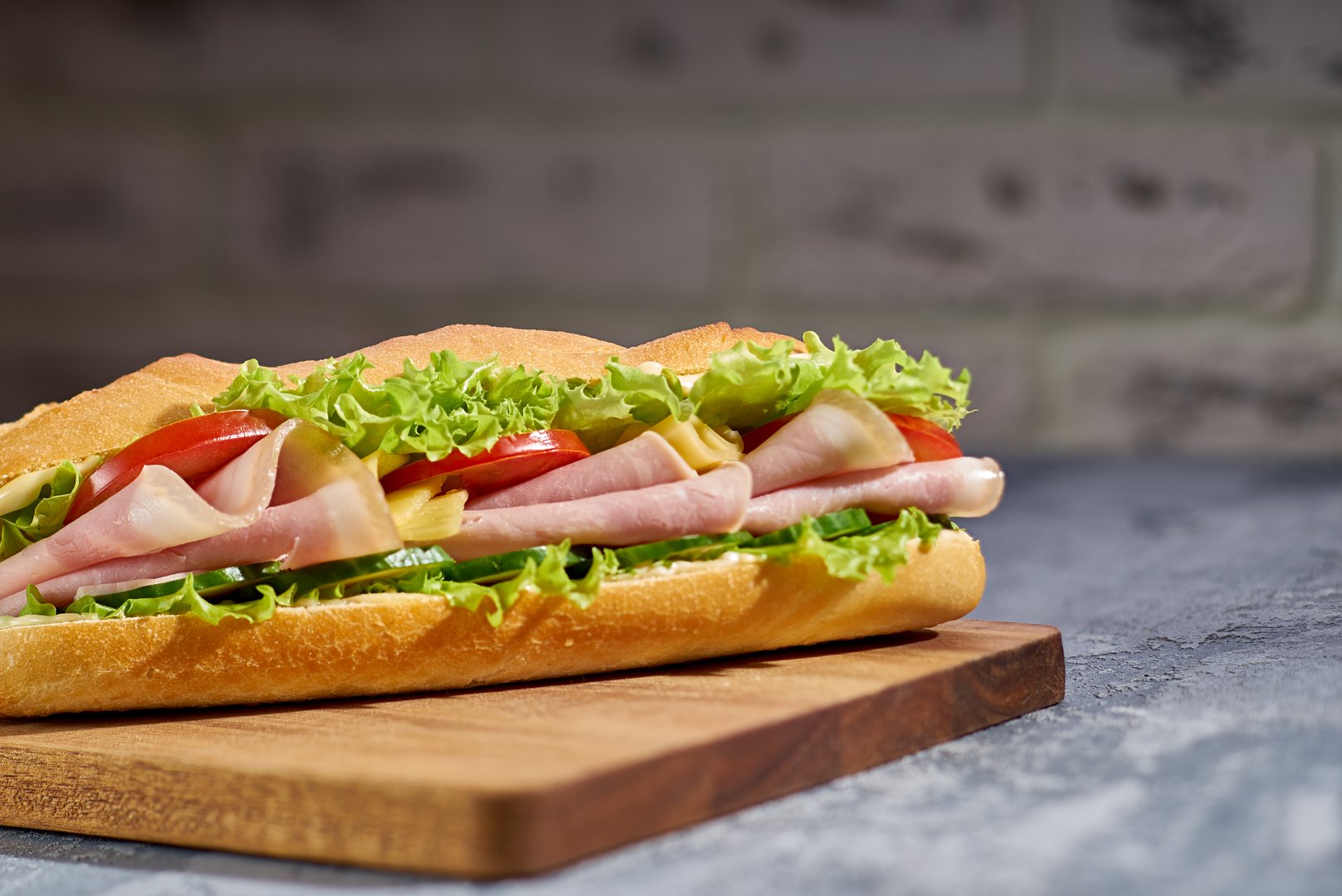 Enjoy a flavorful submarine sandwich with crispy lettuce, ripe tomato, and juicy ham, perfect for any meal