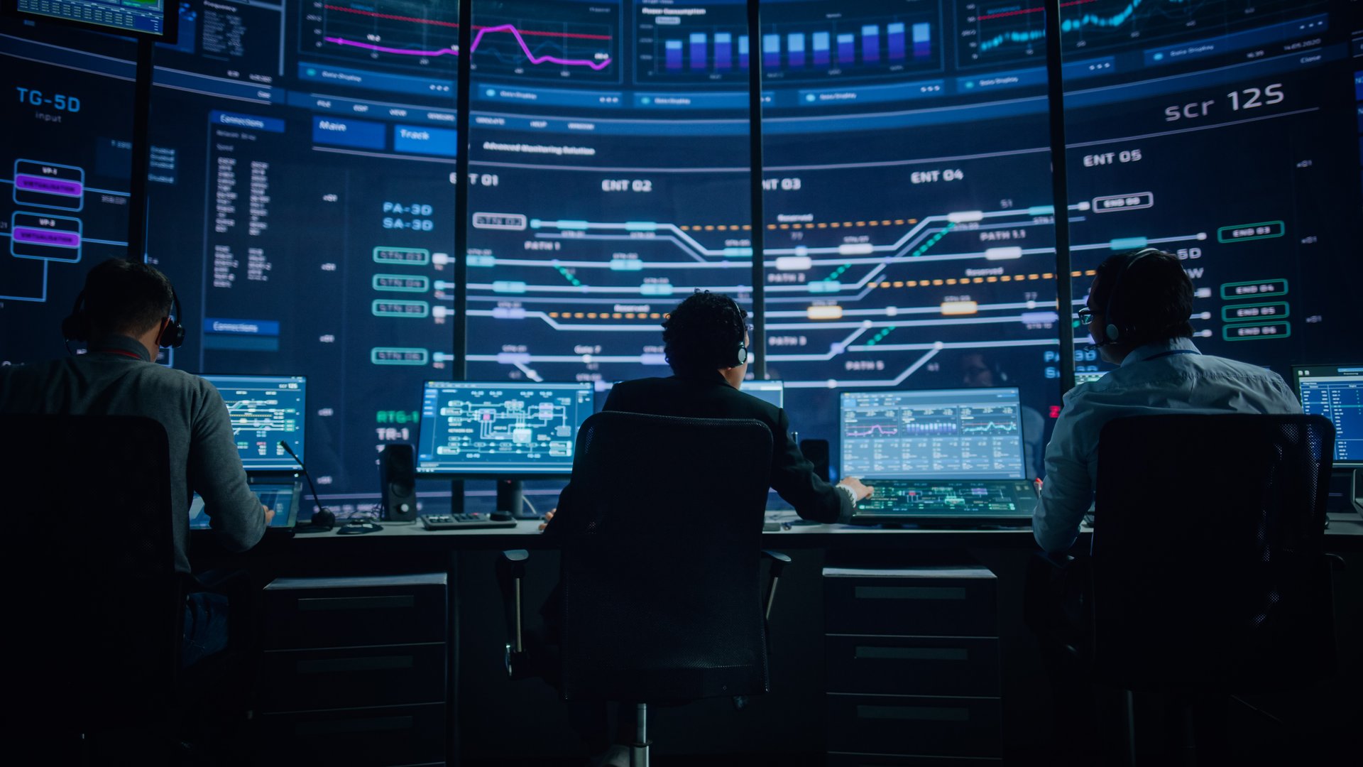 Professional IT Technical Support Specialists and Software Programmer Working on Computers in Monitoring Control Room with Digital Screens with Server Data, Blockchain Network and Surveillance Maps.