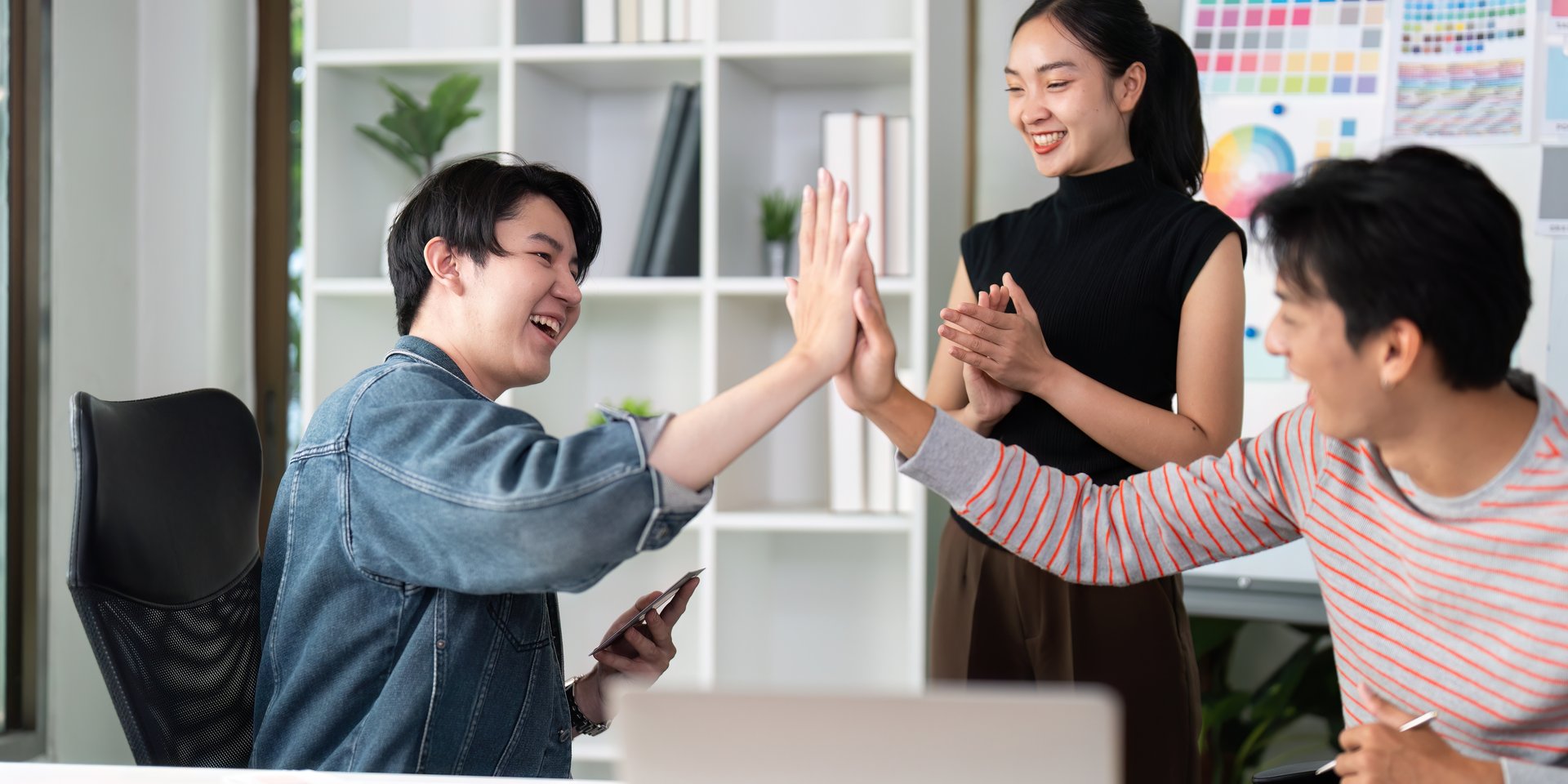 A joyful moment as team members high-five after achieving a breakthrough in their UX/UI project, showcasing teamwork and enthusiasm.