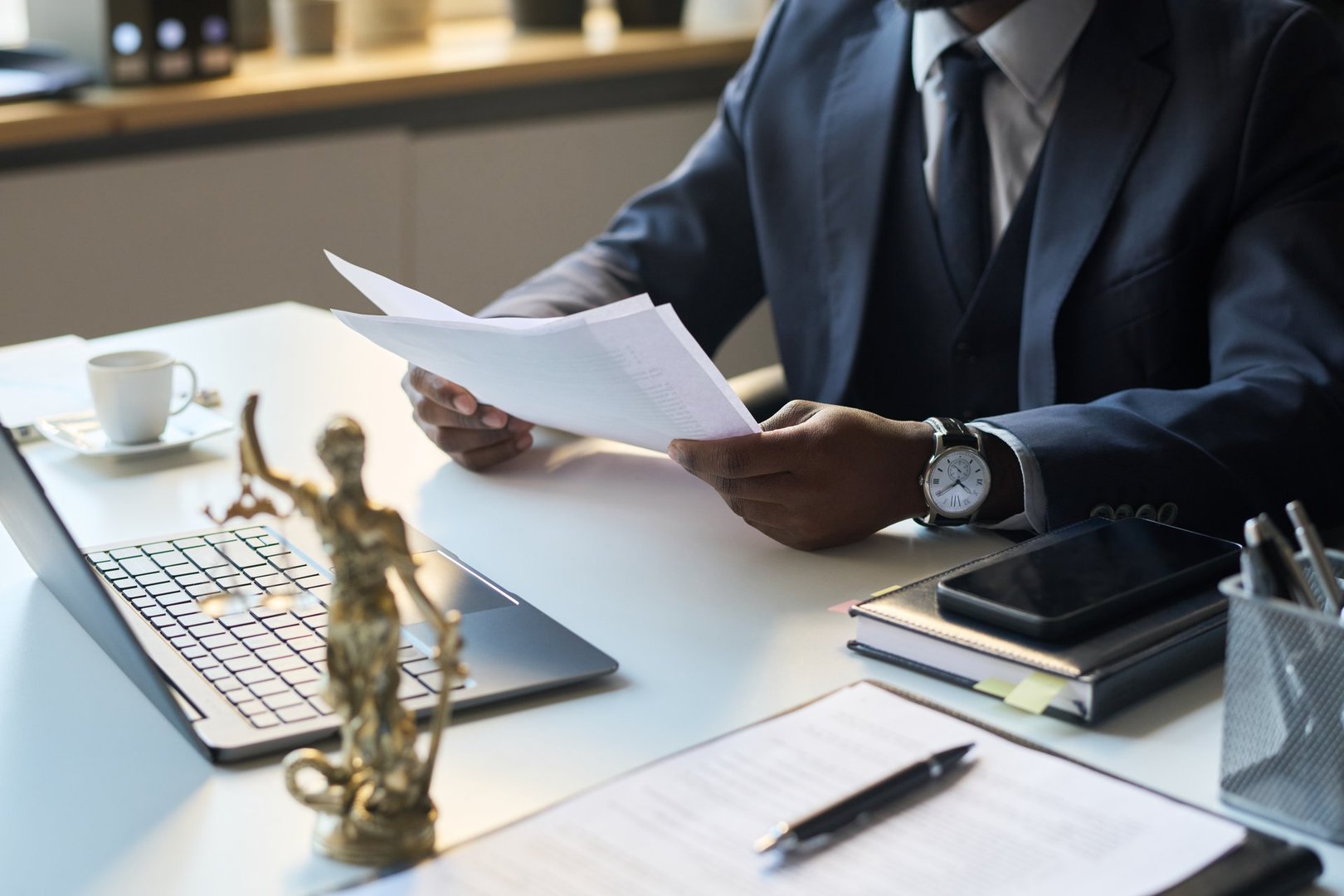 High angle view of unrecognizable Black male legal attorney working in office, looking through paper copy of document