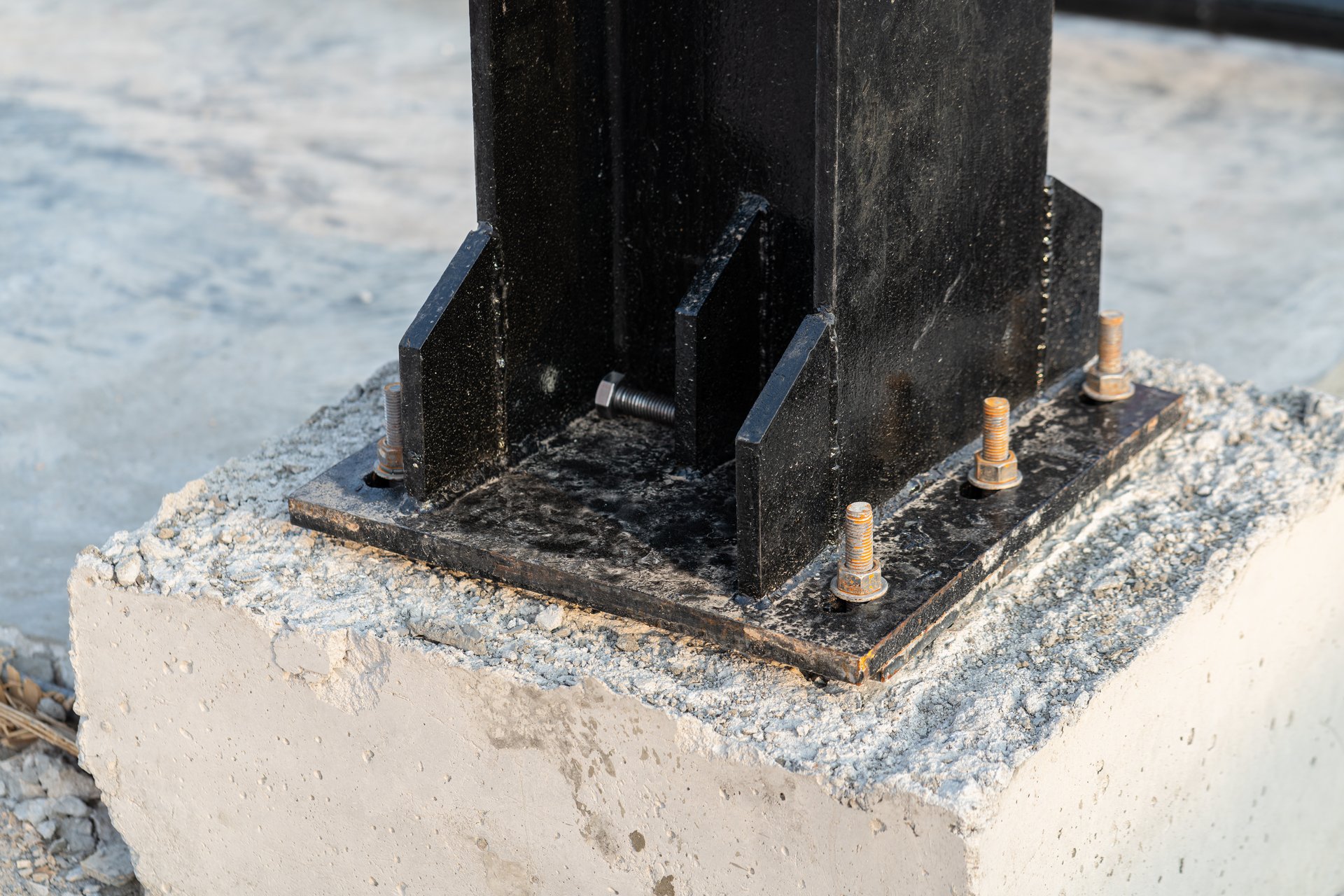 Heavy bolt installed on metal column and concrete base to secure the structure of the new warehouse building . Construction equipment object photo.