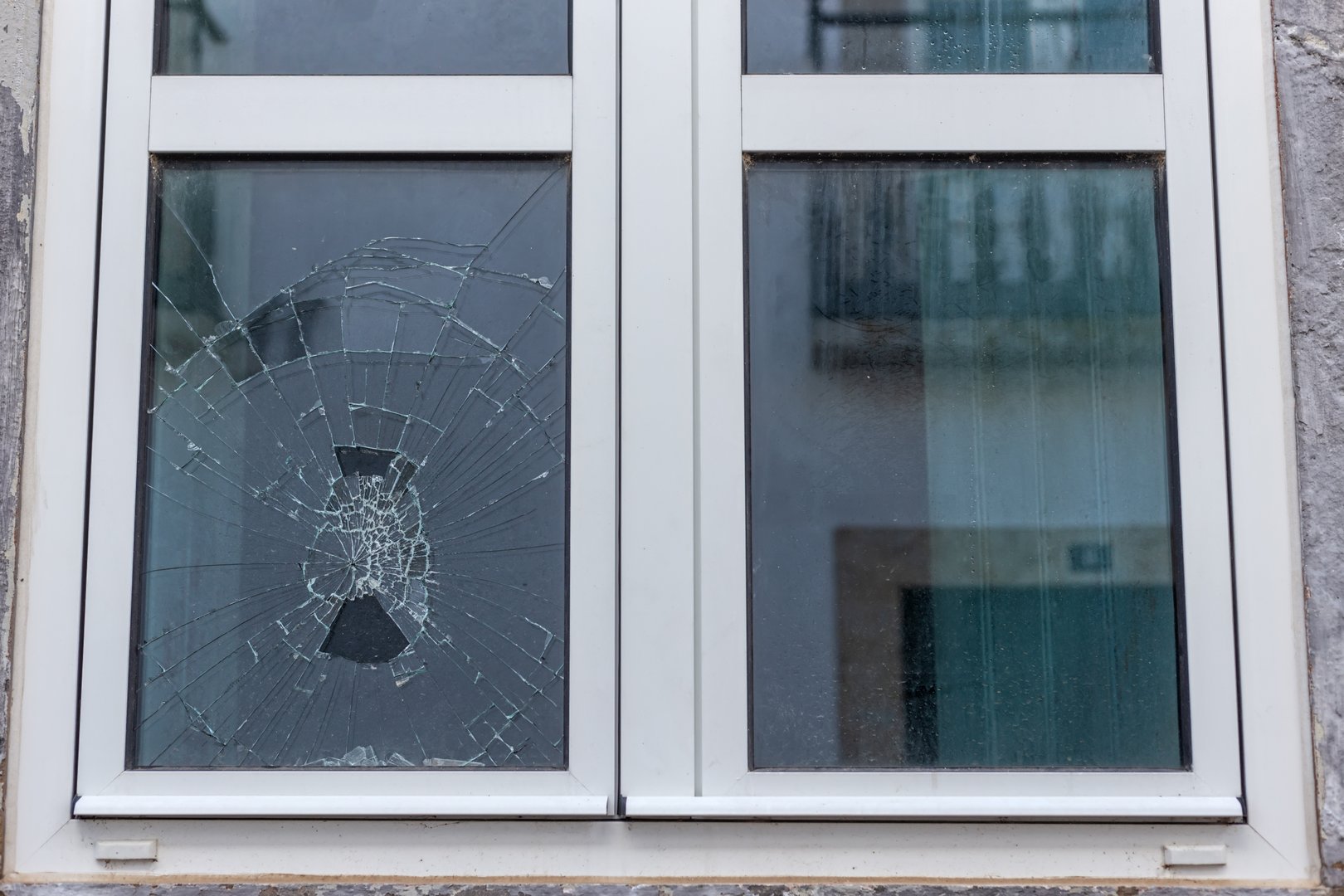 Cracked glass in a plastic vacuum window frame. A damaged window due to vandalism, natural disaster, or accident. High quality photo