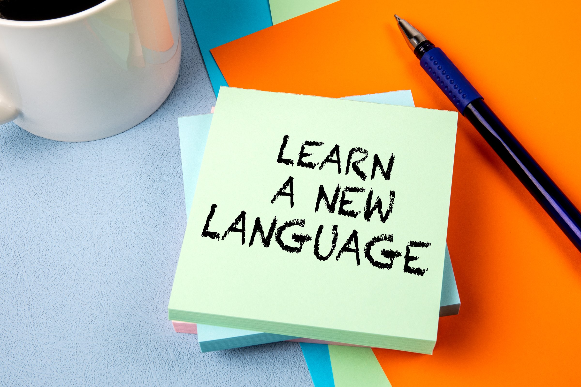 LEARN A NEW LANGUAGE. Notepad with text on office table.