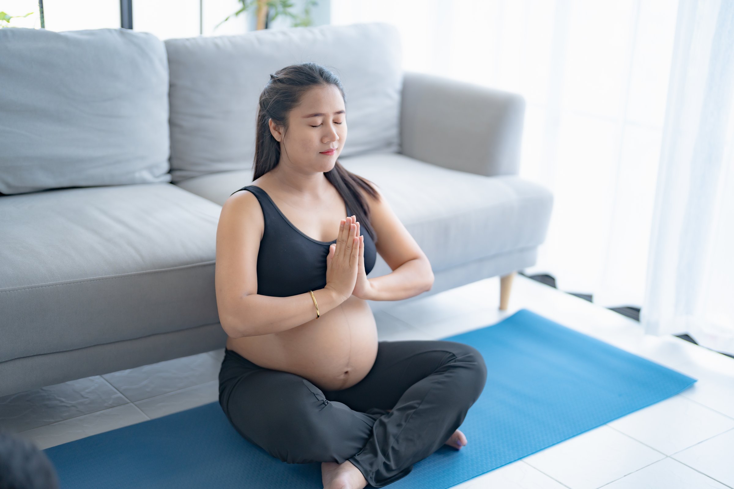 Pregnant asian woman meditation on yoga mat at home relaxation and Self-care during Pregnancy mother mindfulness Positive life moment in pregnancy time.