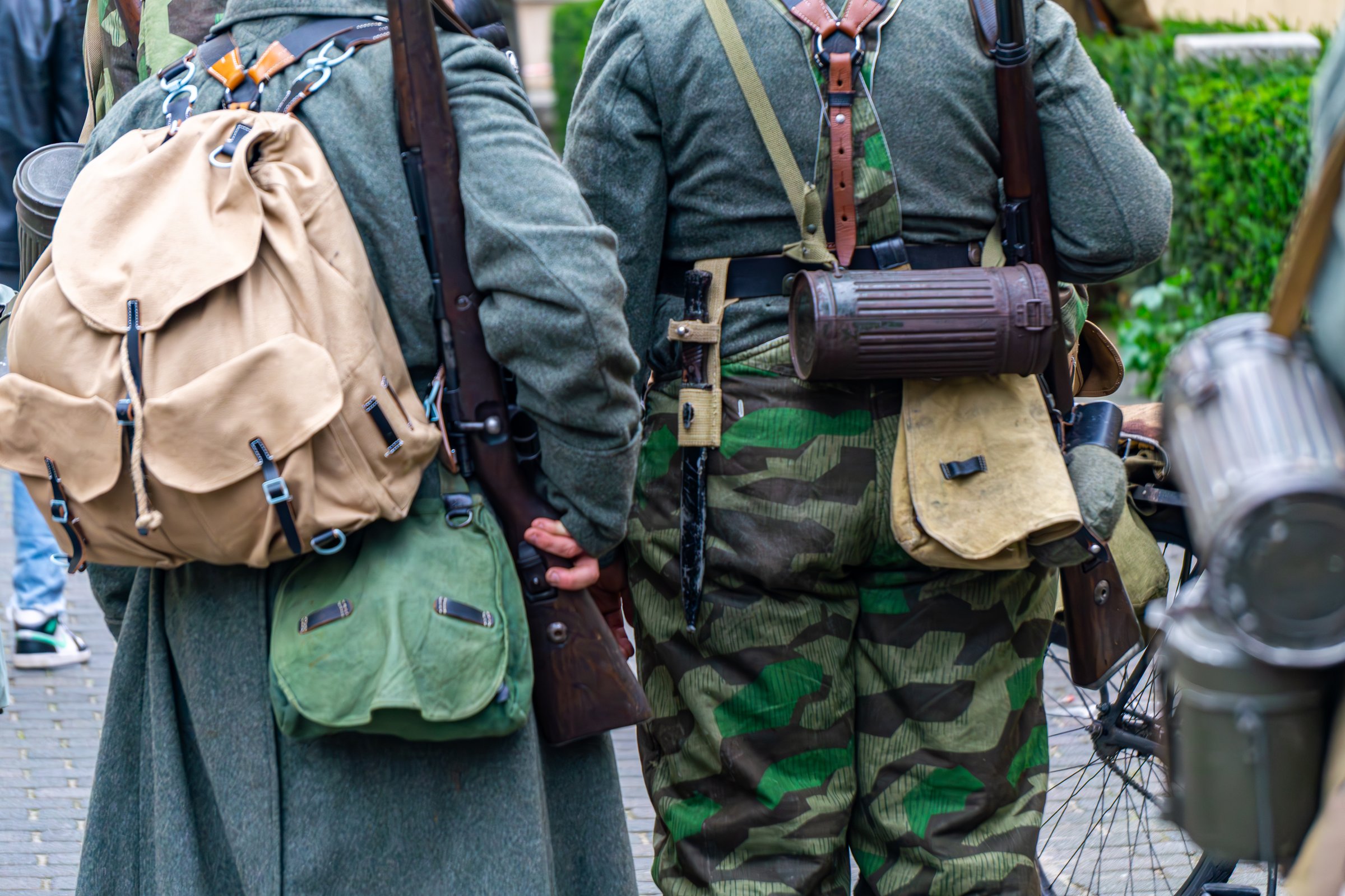 Wehrmacht infantry gear details, mountain rucksack and gas mask canister, German historical reenactment uniforms, WWII soldier equipment and splittertarn camouflage close-up.