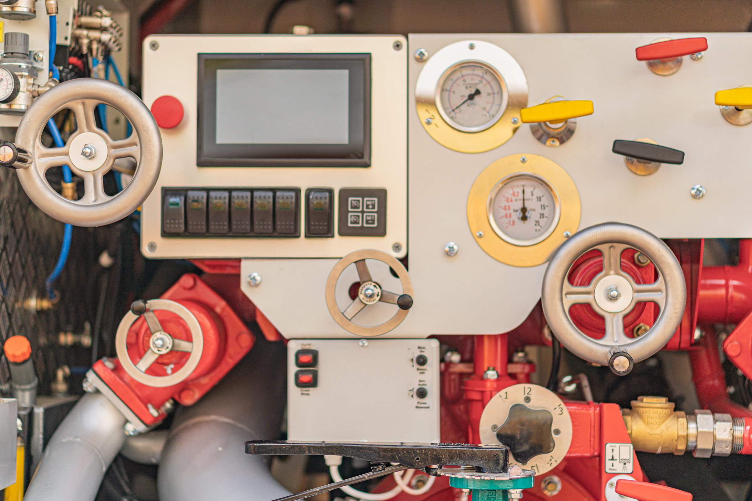 Close-up of firefighters rescue equipment control unit, featuring levers, dials, switches, and gauges in a gray, black, and red color palette Industrial setting with metallic pipes and structures