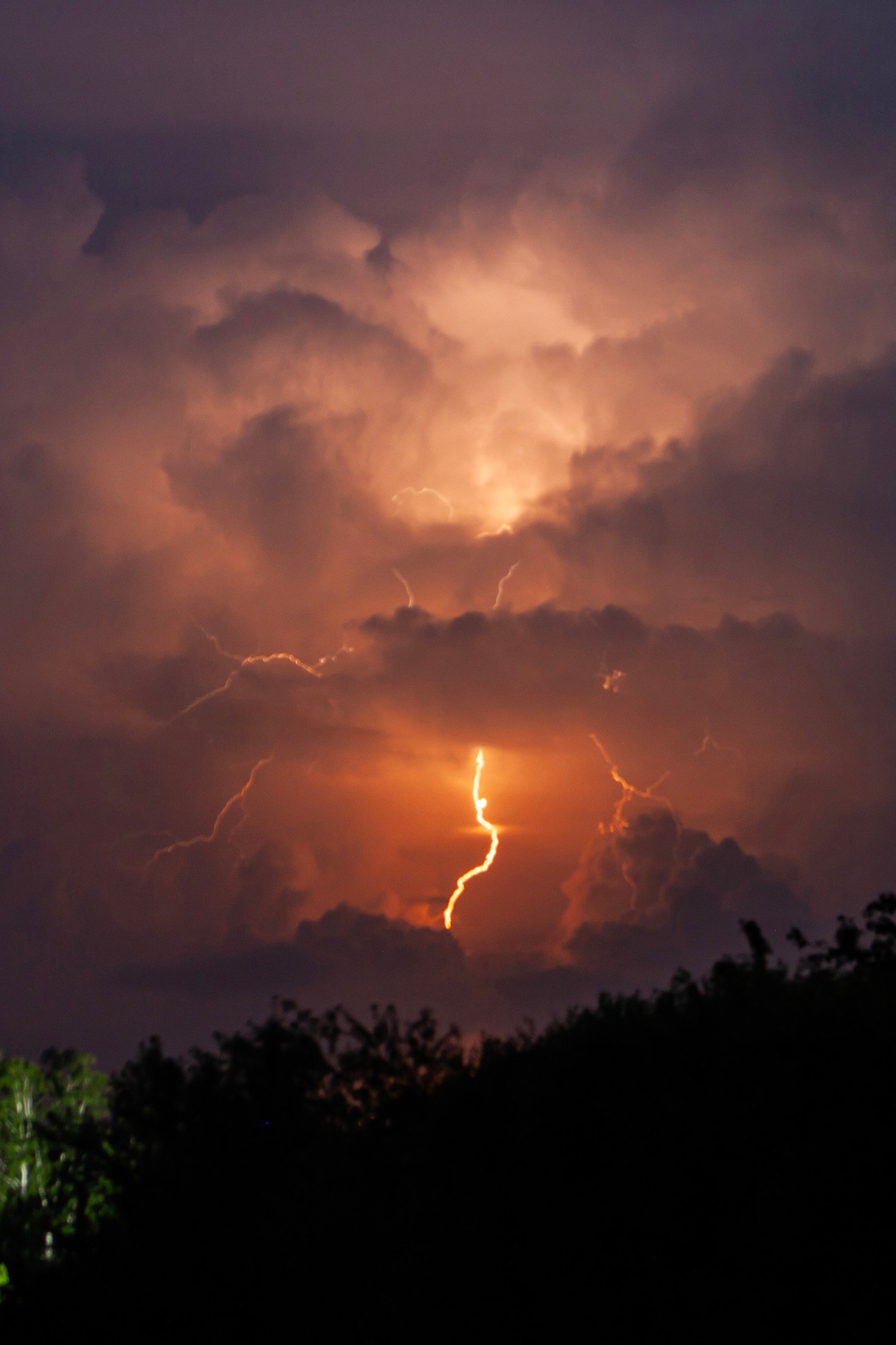 beautiful lightning during a thunderstorm at night in a forest that caused a fire, against a dark sky with rain