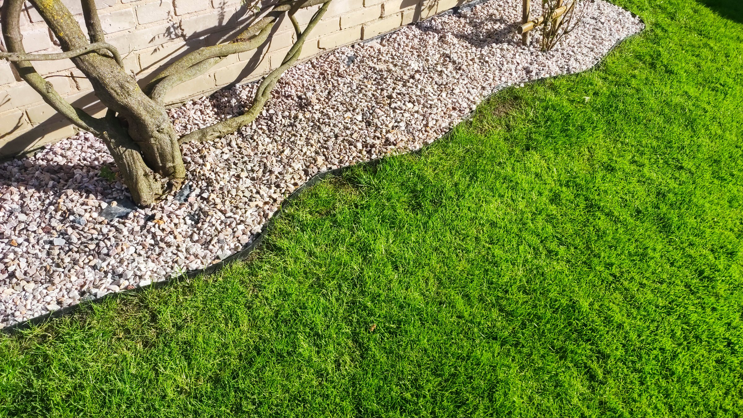 Lush green lawn with an edging of small garden stones
