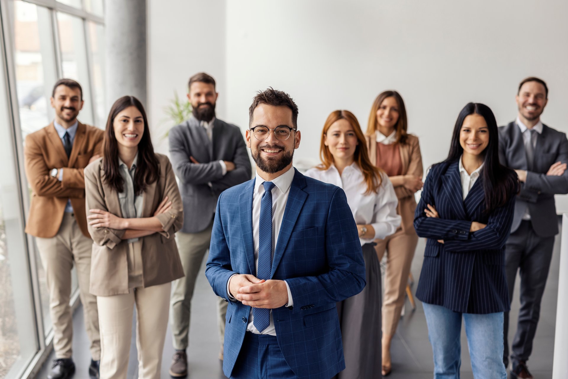 Portrait of smiling confident executive standing with his leadership team at corporation.