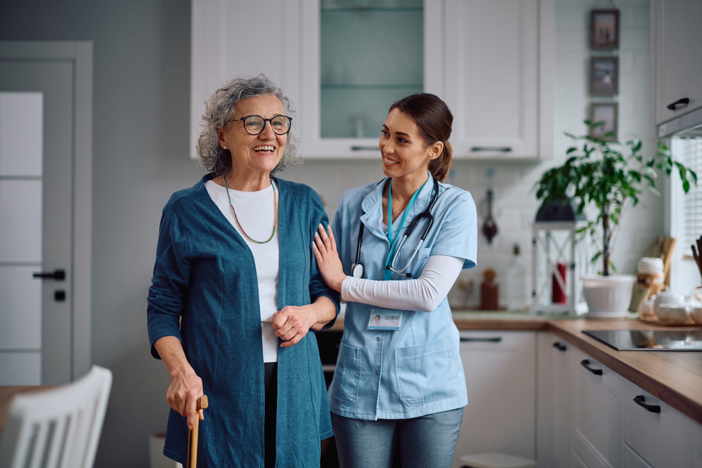 Happy home caregiver assisting senior patient