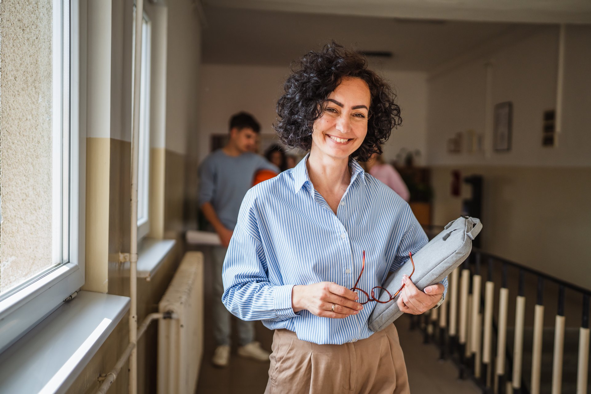 mature female teacher walk confidently at school hallway with handbag