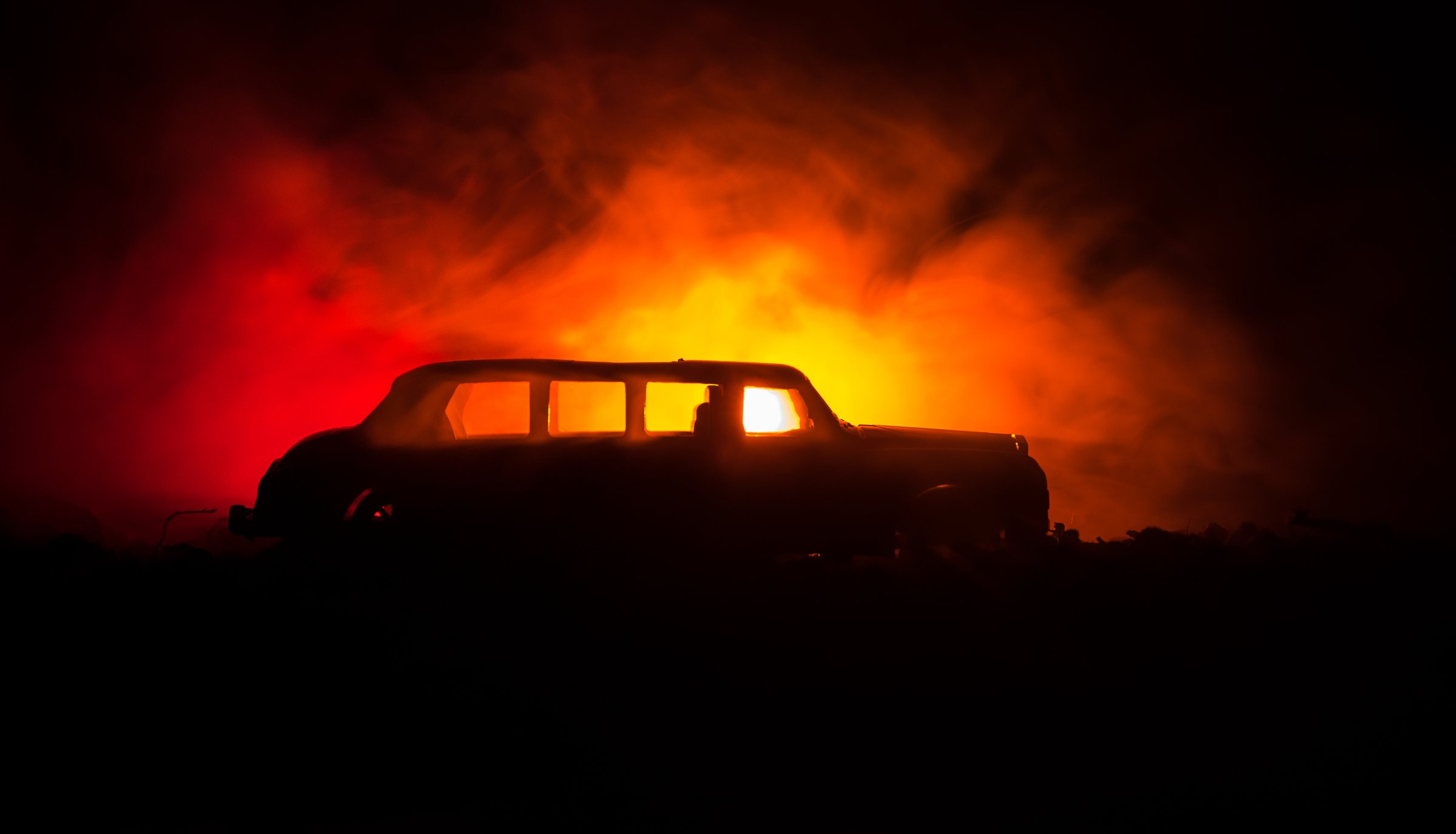 The car in the shadows with glowing lights in low light, or silhouette of limousine car dark background. Selective focus