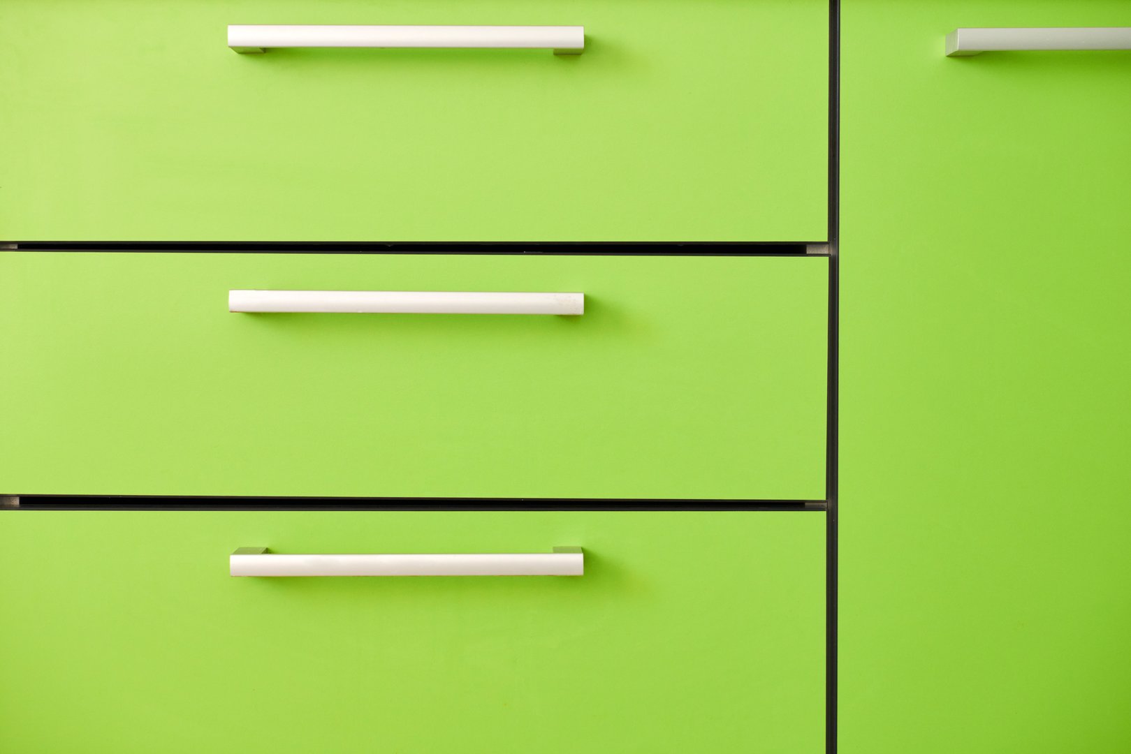Light green kitchen drawers. Closed drawers with different kitchenware and cookware. Stylish and minimal kitchen interior