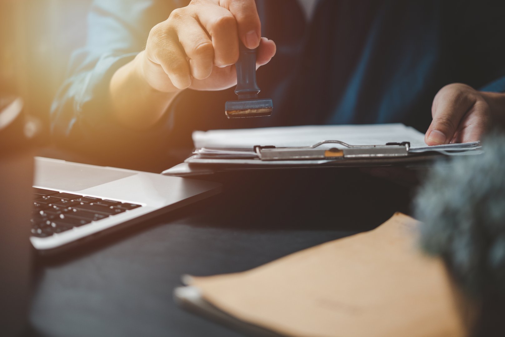 Man stamping approval of work finance banking or investment marketing documents on desk.