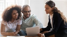 Two people reviewing documents with a business professional in an office setting.