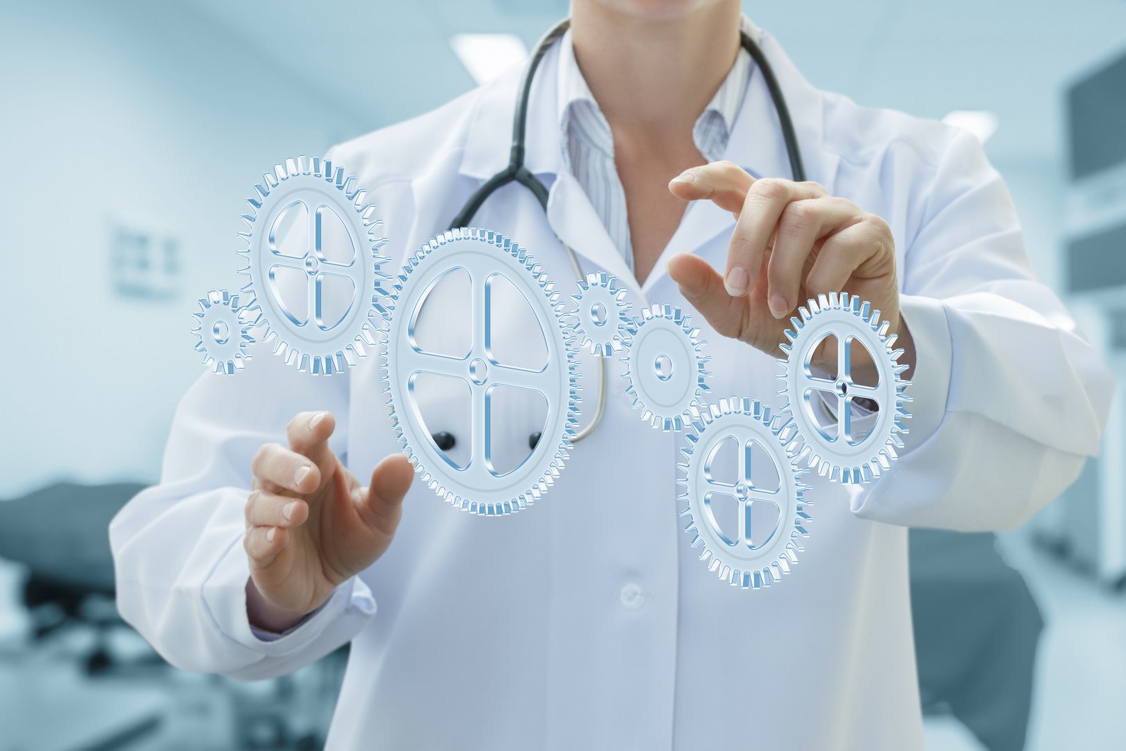 A healthcare professional in a lab coat touches a transparent holographic display of rotating gears. The setting suggests a modern medical environment, emphasizing innovation in healthcare.