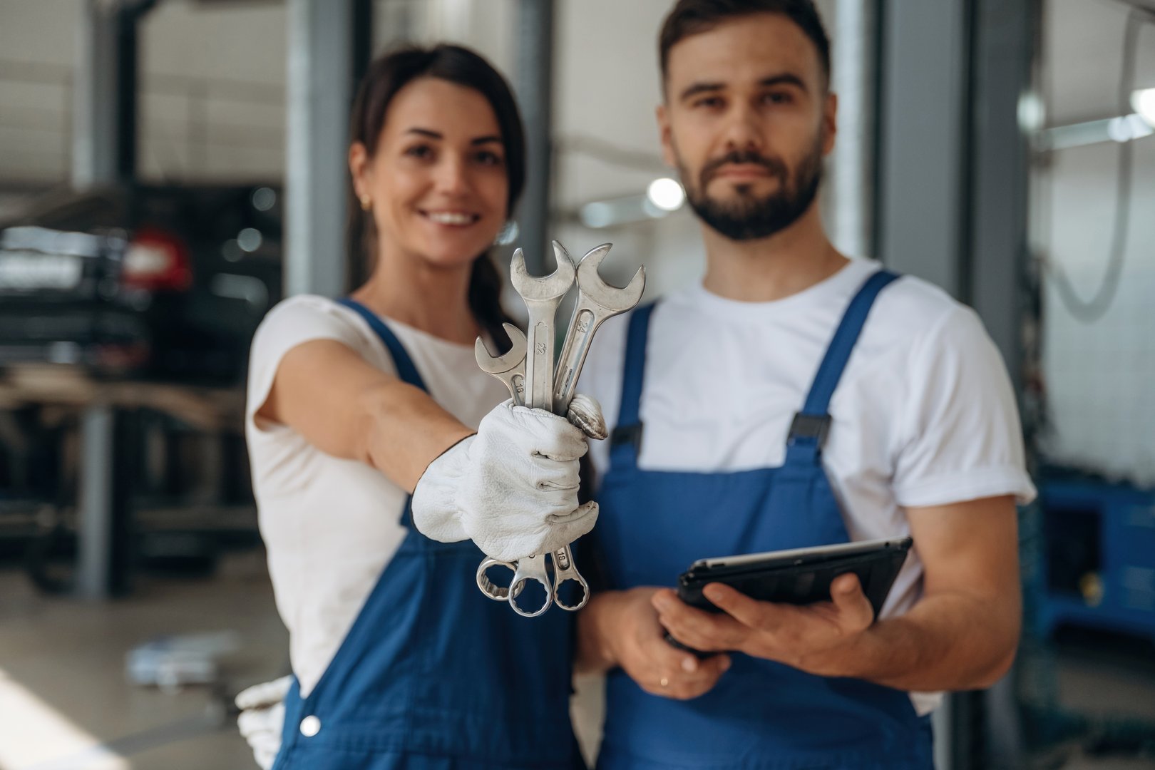 Showing the tools. Auto repair shop employees are working together. Man and woman.