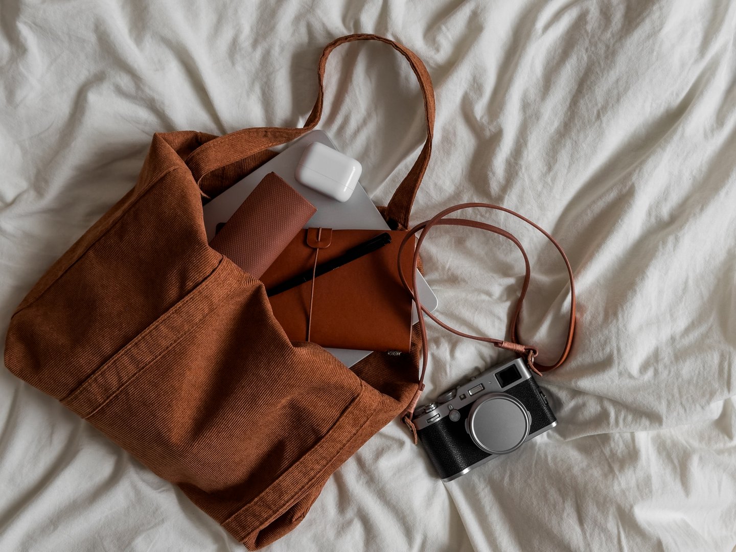 Corduroy bag, laptop, camera, notebook - women's stylish accessories on a light background, top view