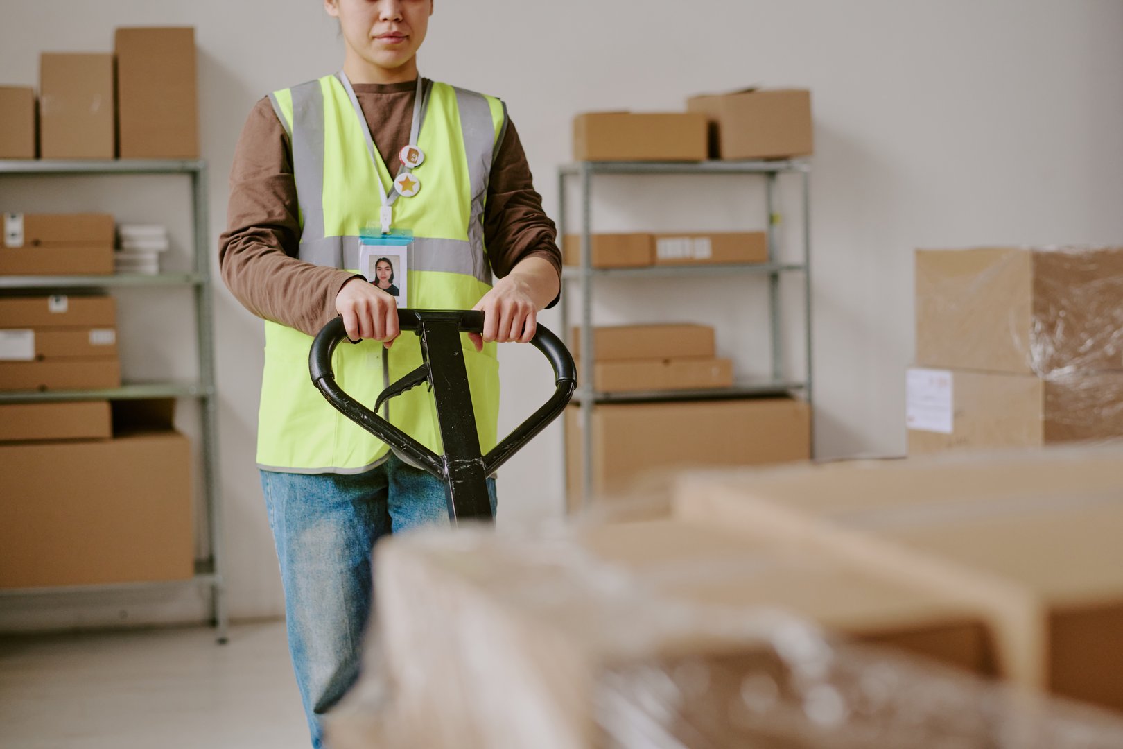 Worker adjusting equipment in warehouse, surrounded by shelves and boxes, focused on task at hand, showcasing workplace environment and responsibilities