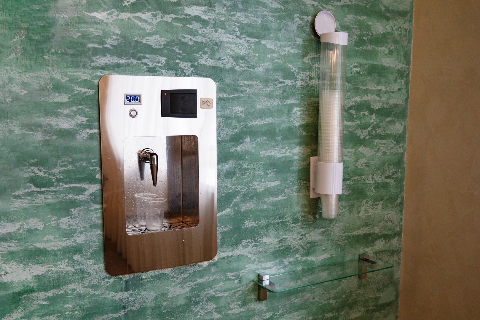 Close-up of water dispenser with a plastic cup filled with mineral water.