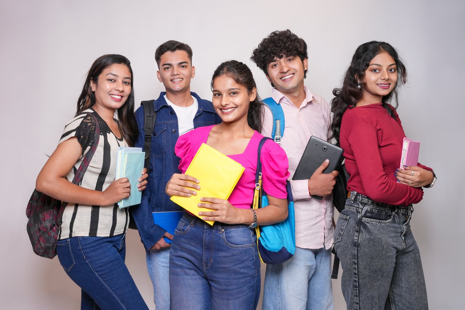 Portrait of happy indian college students standing isolated on white background. Smiling young asian adult gen z girls and boys looking at camera. Education.
