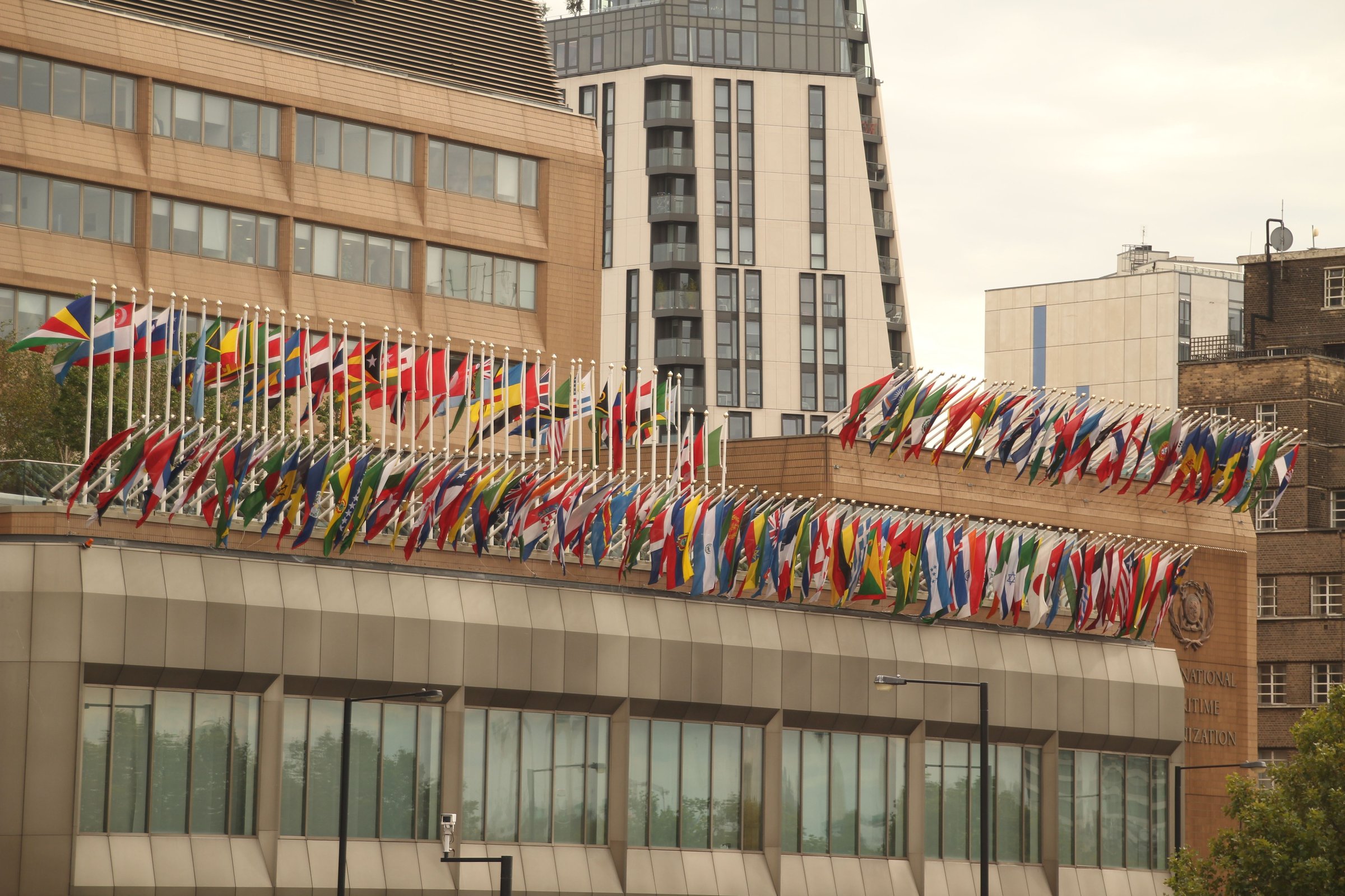 Flags of various countries displayed on the International Maritime Organization building in London, showcasing global unity and diplomacy.