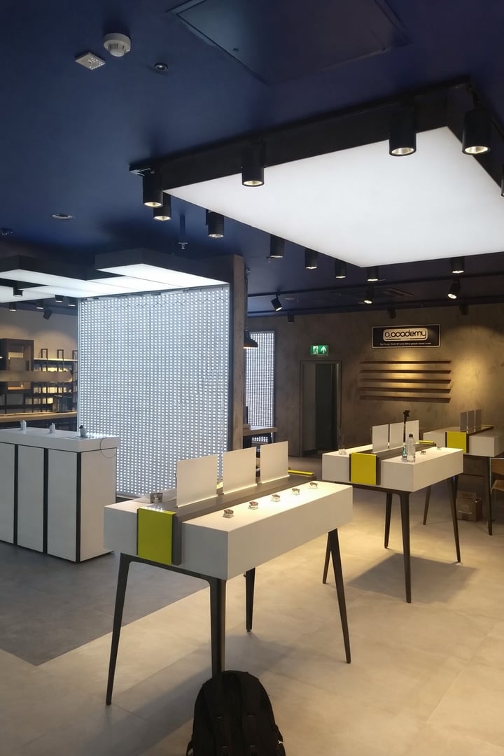 A bathroom with a blue and gold pattern wallpaper, gold faucet and light fixtures, and a white cabinet and sink.