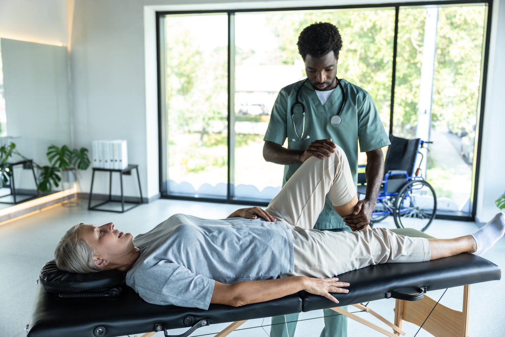 Legs stretching. Female patient lying on a couch while male doctor working on her legs stretching