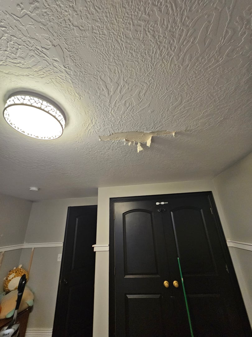 Ceiling damage from flood showing hole cut in drywall to drain water
