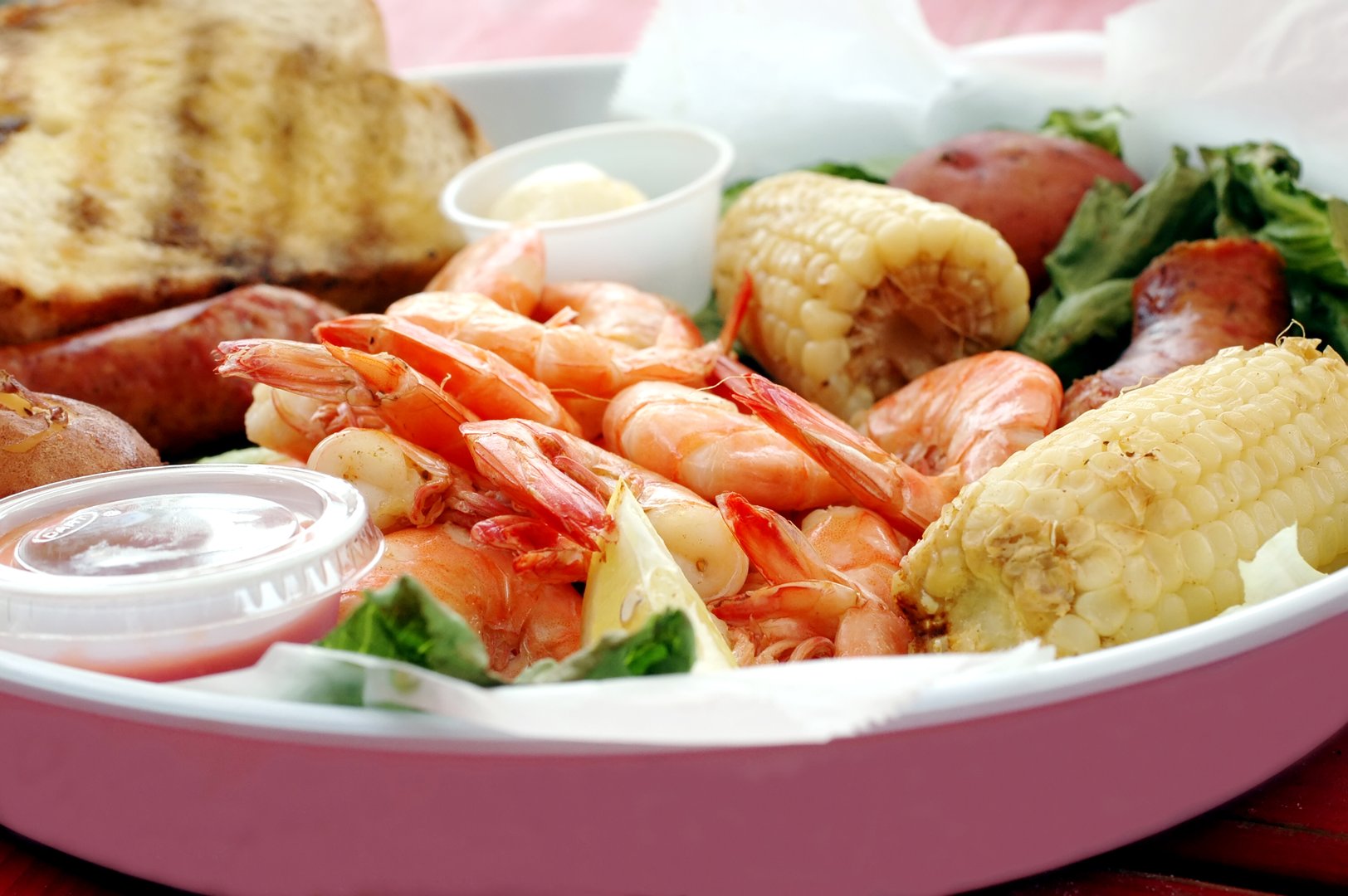 Shrimp boil with corn, sausage, potatoes, and bread.